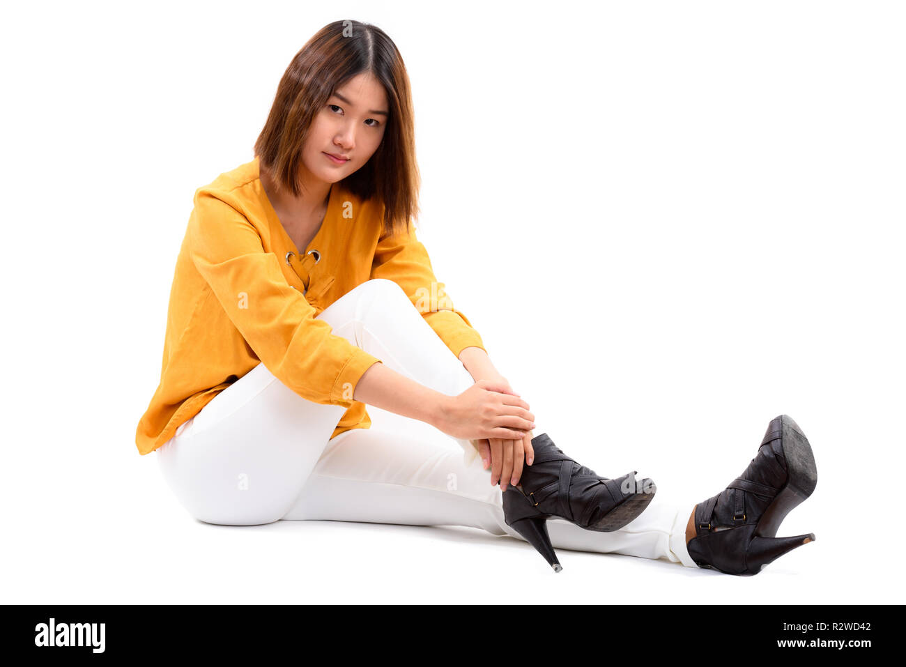 Studio shot of young beautiful Asian woman sitting on the floor Banque D'Images