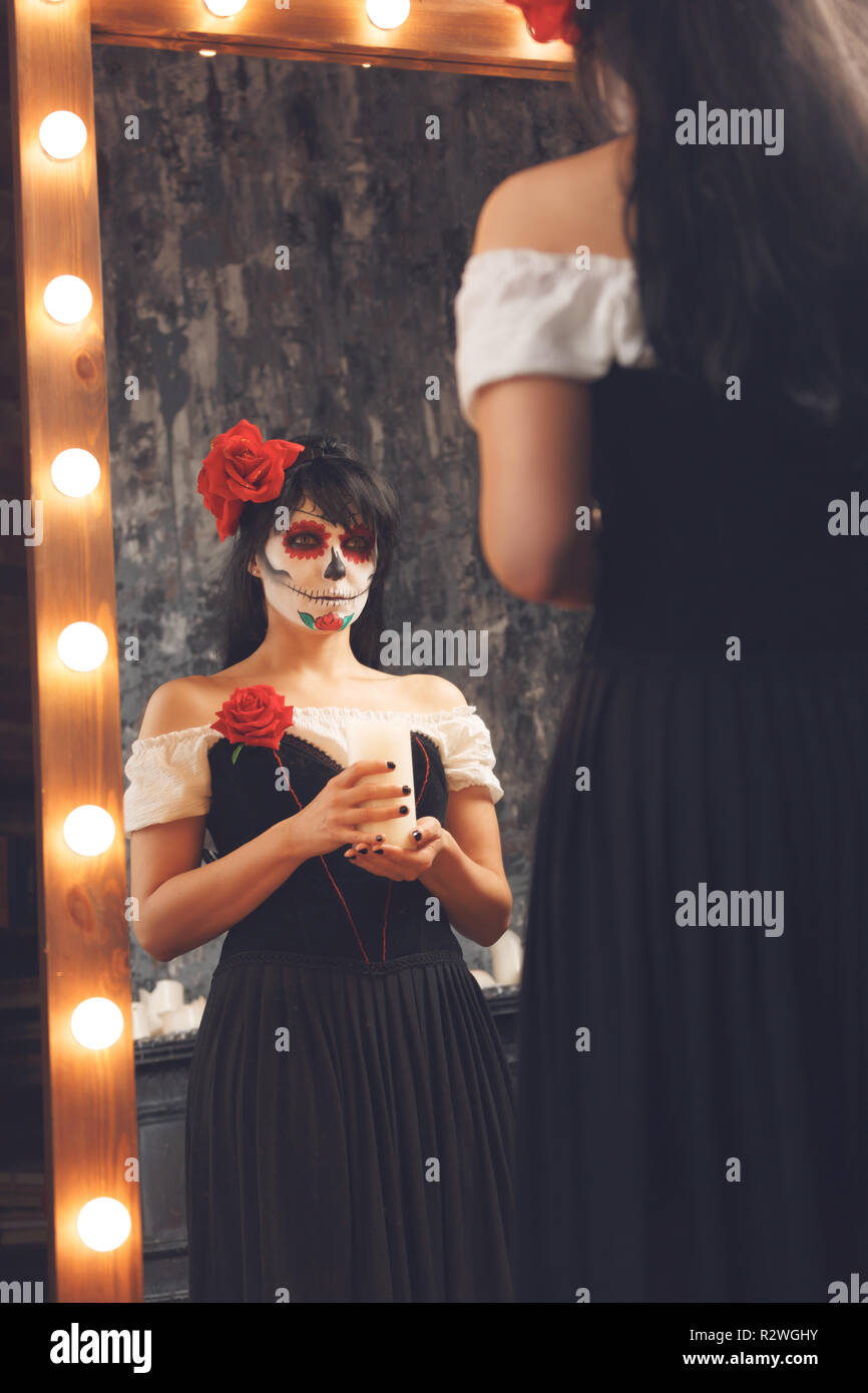 Droit de zombie girl avec un visage blanc à côté de miroir et lumières de gravure en noir Prix Banque D'Images