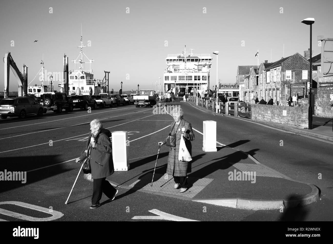 Deux vieilles dames à la retraite de la circulation aux passages à niveau en utilisant des bâtons et transportant des glaces dans les mains à l'île de Wight Yarmouth Ferry terminal park Banque D'Images