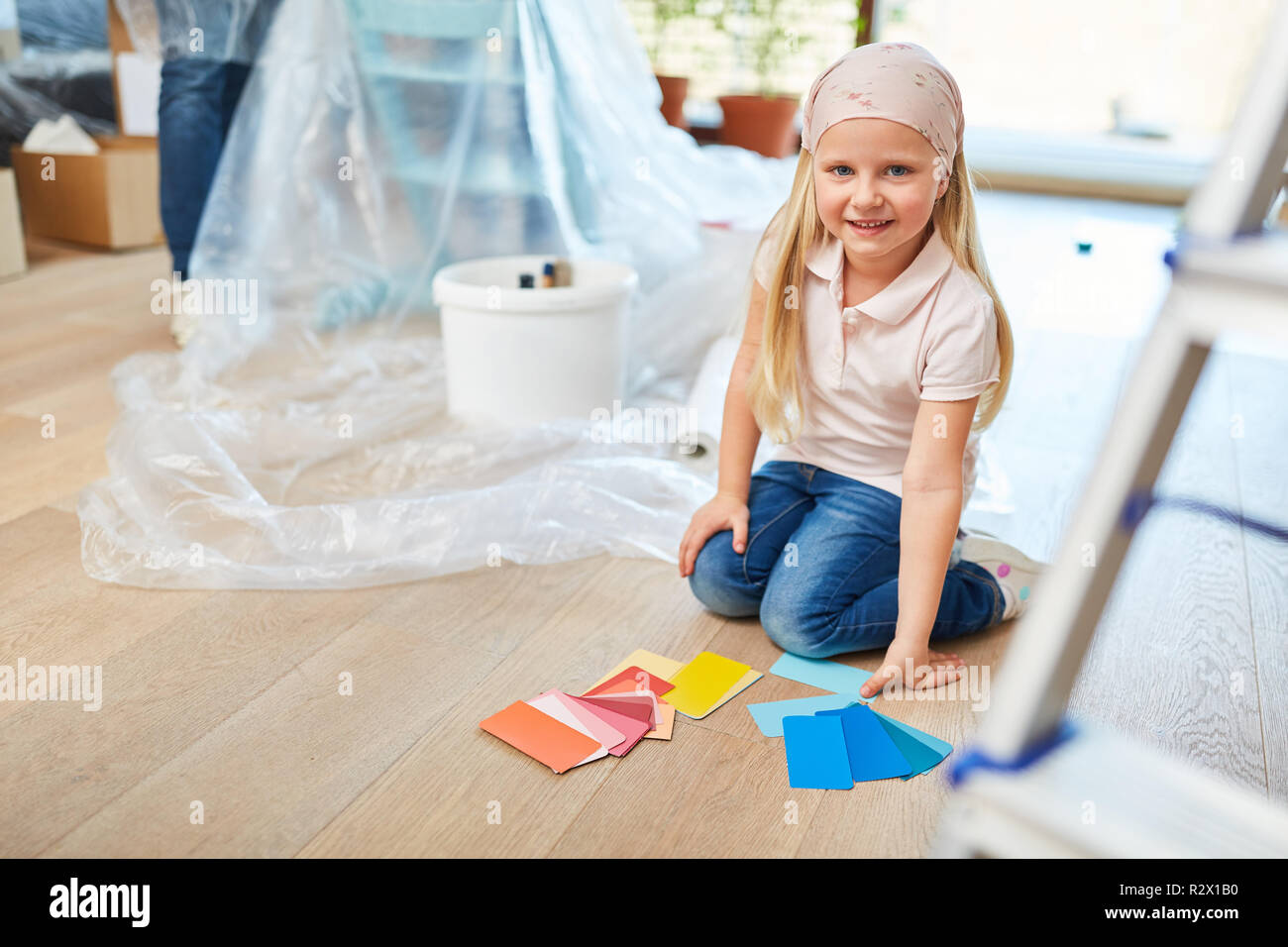 Petite fille en peignant dans maison neuve avec de la peinture murale à choisir de Banque D'Images