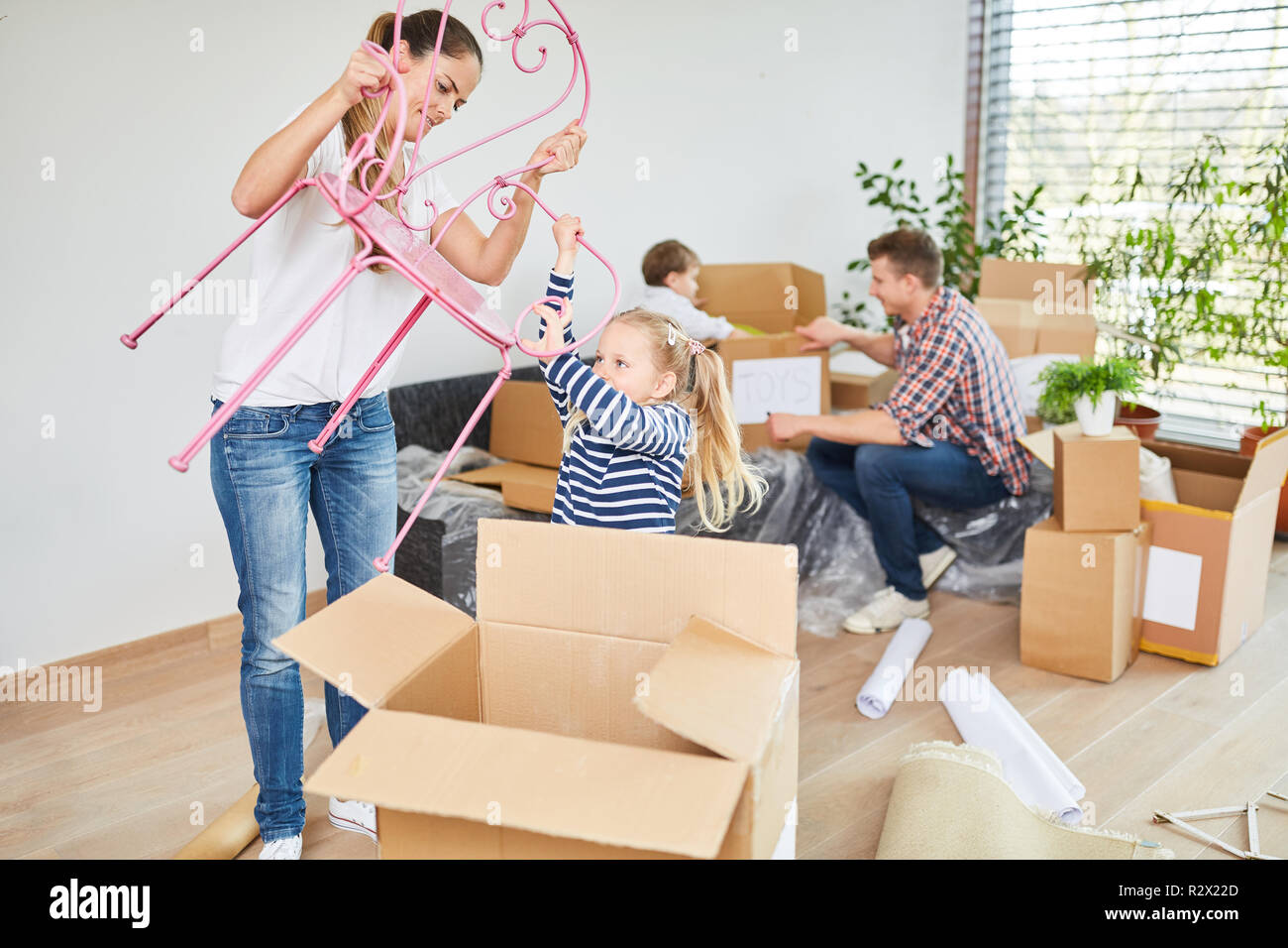 Les enfants et les parents à déballer des cartons lors du déplacement dans la nouvelle maison Banque D'Images