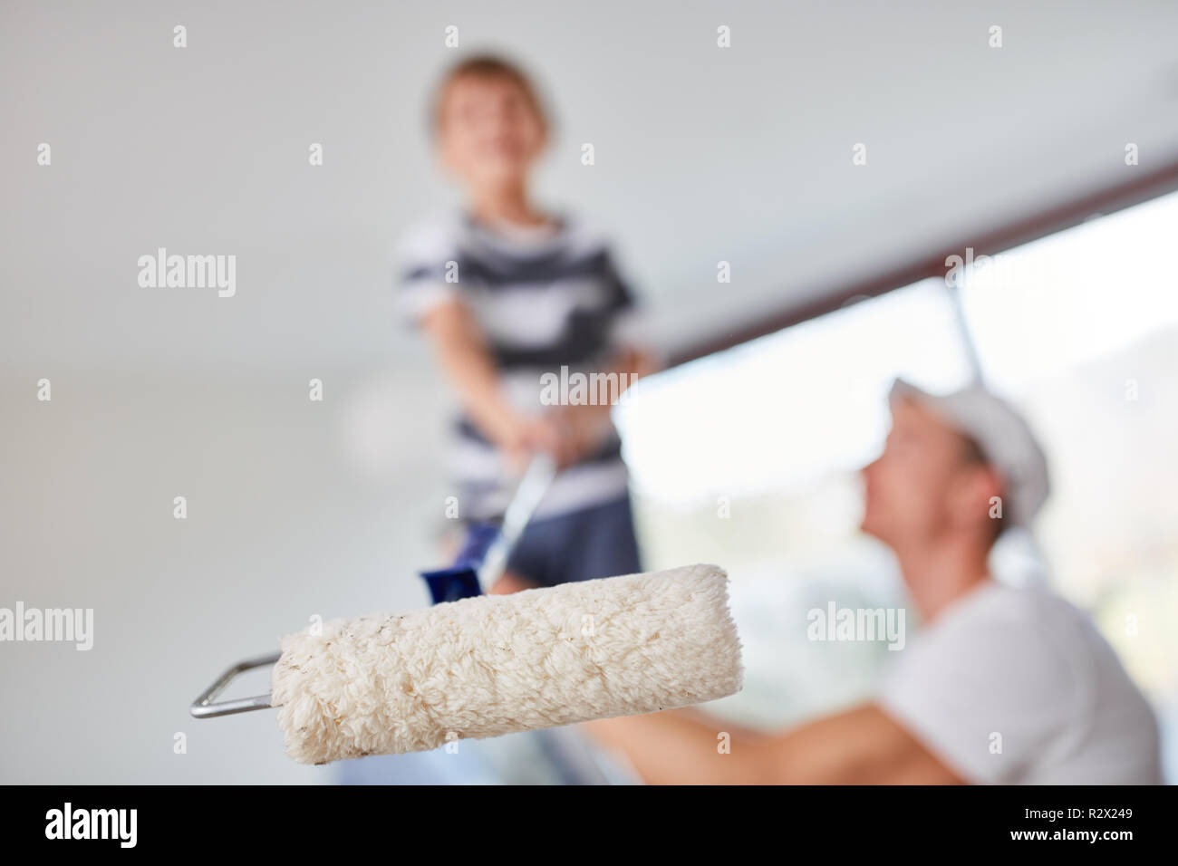 Sur l'échelle de l'enfant peint avec rouleau à peindre avec l'aide de son père dans la nouvelle maison Banque D'Images