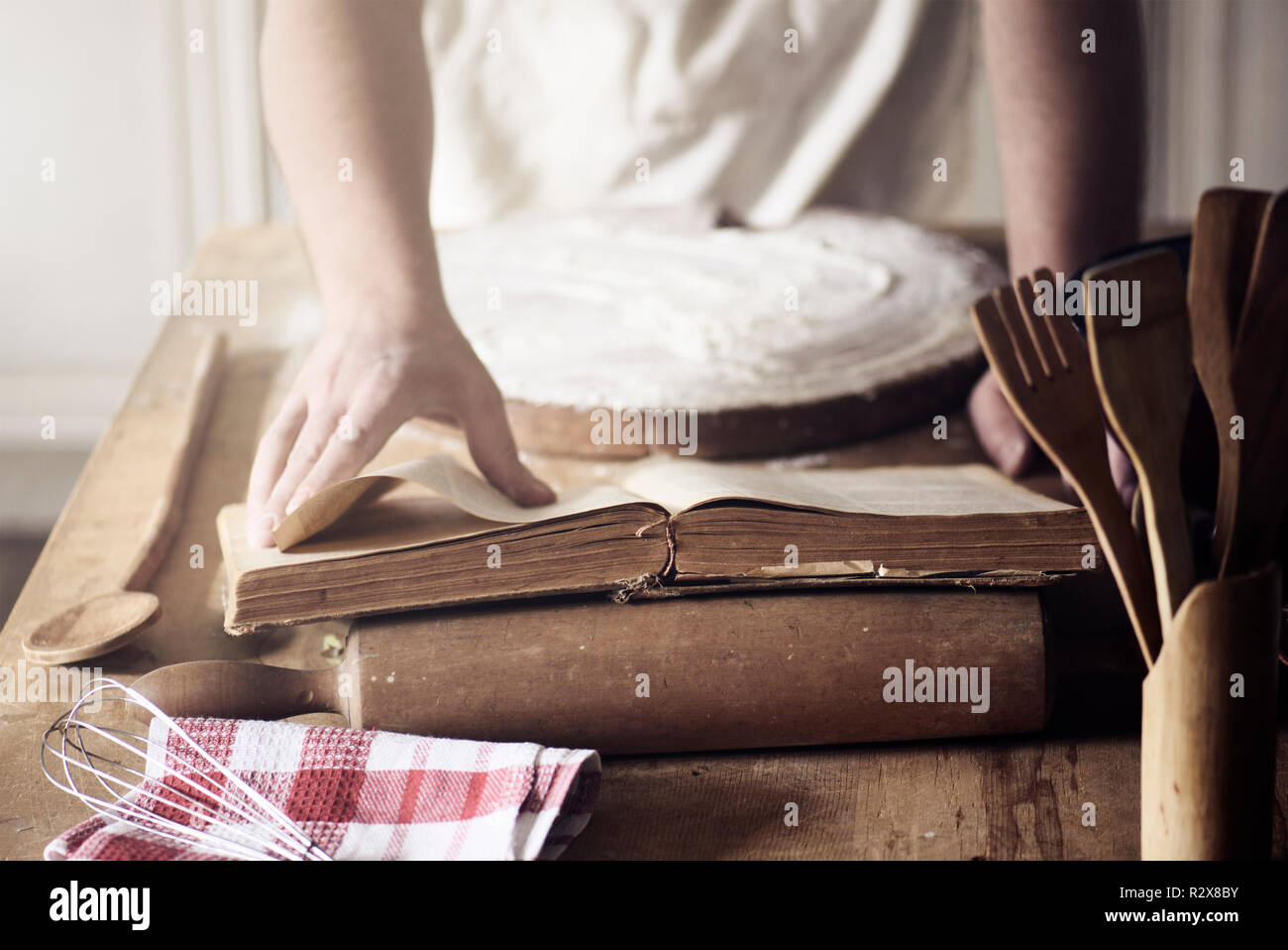 L'homme préparation recette traditionnelle du vintage cookbook. Maison de cuisson Chef pâte sur la table de la cuisine. Banque D'Images