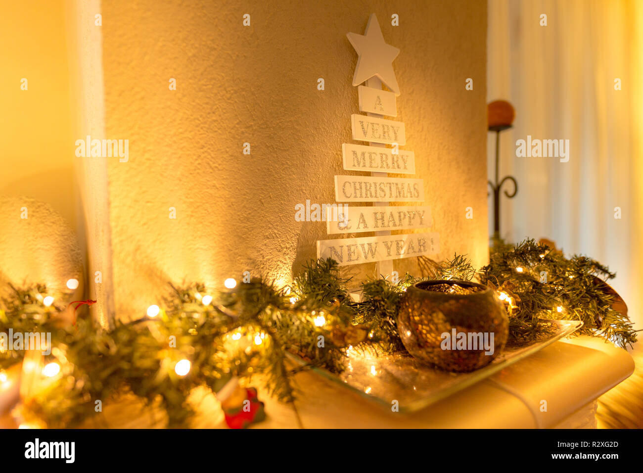 Sapin de Noël avec décorations vintage près de la cheminée, lumières à DEL, décoration dorée pour Noël Banque D'Images