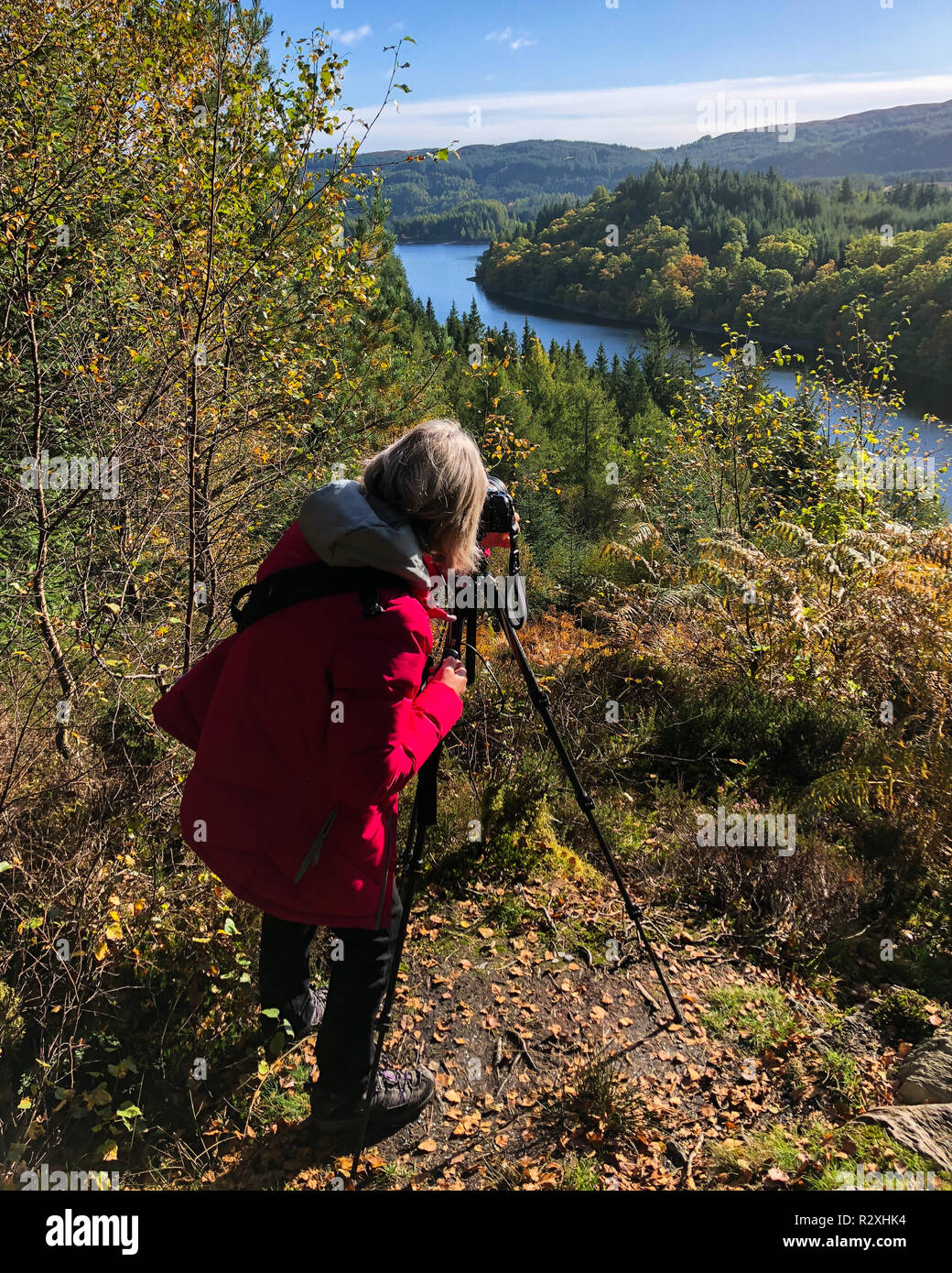 Femme photographe mise en place sur le trépied de l'appareil photo pour prendre une photo de paysage écossais, Trossachs, Scotland UK Banque D'Images
