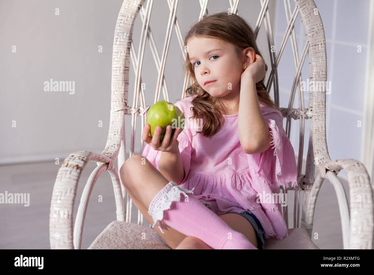 Une petite fille est assise sur une chaise et milkshake potable Banque D'Images