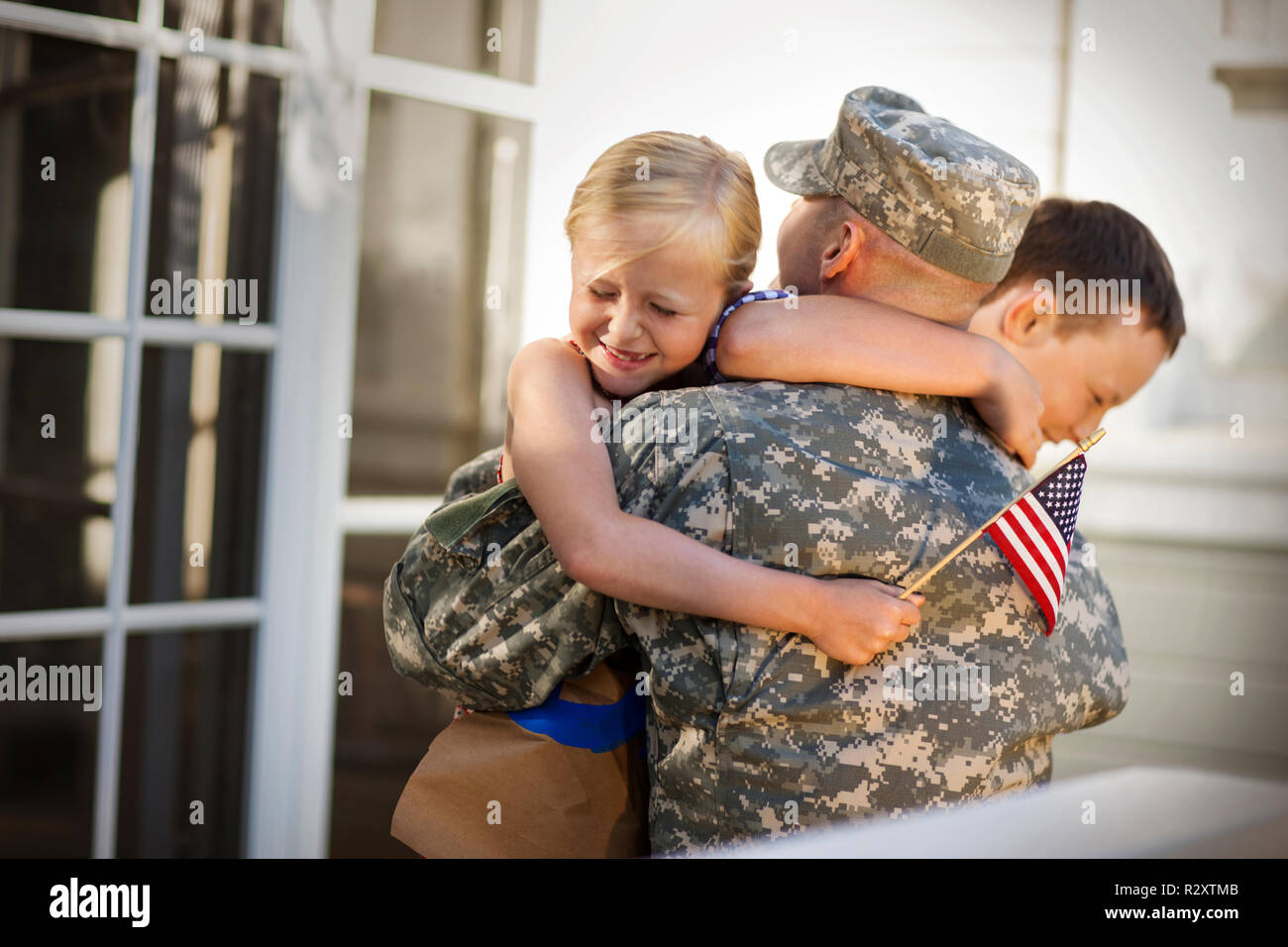 Mid adult man vêtu d'un uniforme militaire est accueilli par ses enfants. Banque D'Images