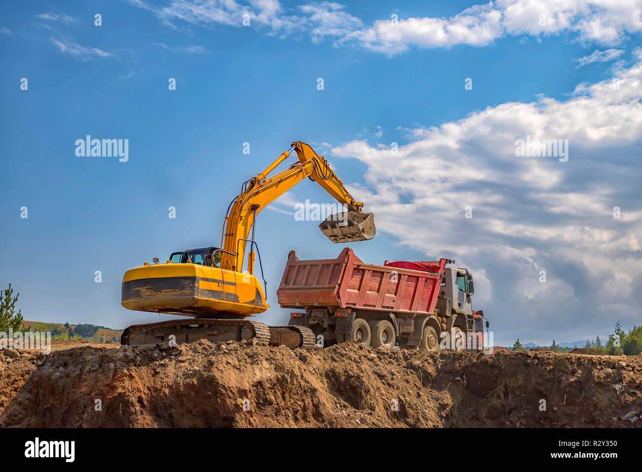 Excavatrice jaune et camion-benne vide sur le chantier de travail Banque D'Images