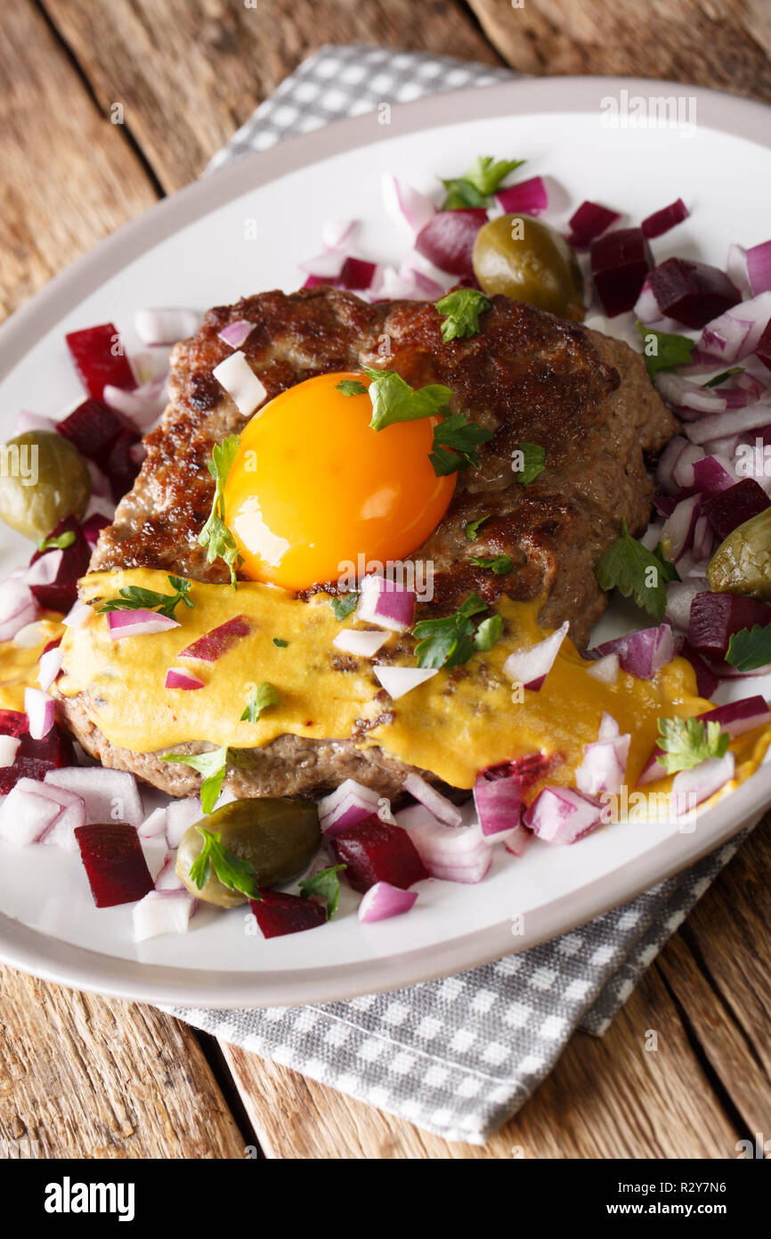 Une cuisine danoise : steak ou Pariserbof parisien avec des légumes et la moutarde gros plan sur une plaque verticale sur la table. Banque D'Images