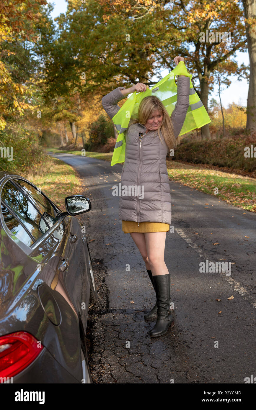 Automobiliste femme par sa voiture s'efforce de mettre sur un gilet de  sécurité réfléchissant Photo Stock - Alamy