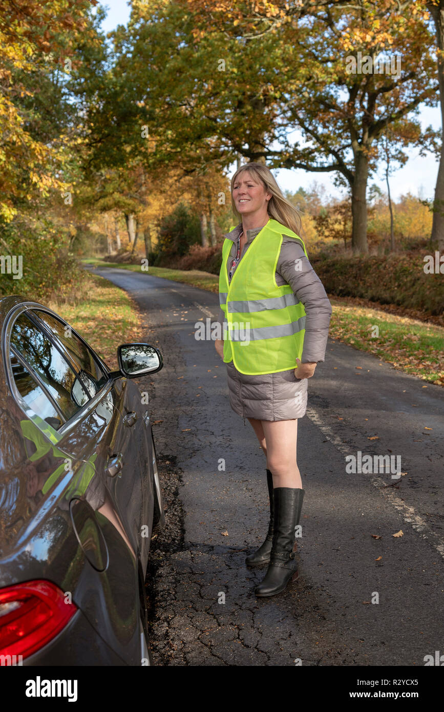 Automobiliste femme par sa voiture en mettant sur une veste de sécurité réfléchissante Banque D'Images