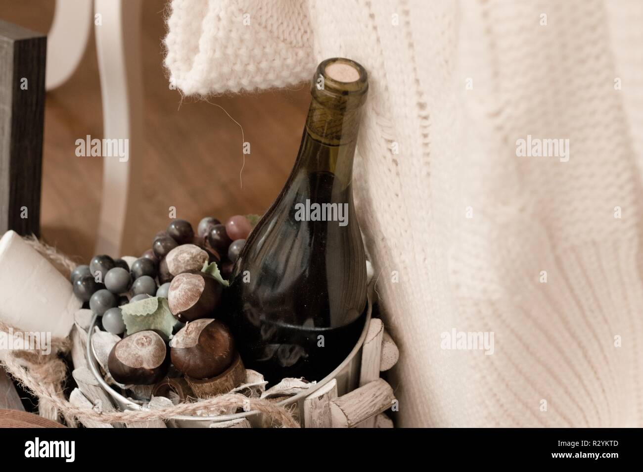 Une bouteille de vin avec les châtaignes dans un basken en bois et un pull blanc (Marches, Italie) Banque D'Images