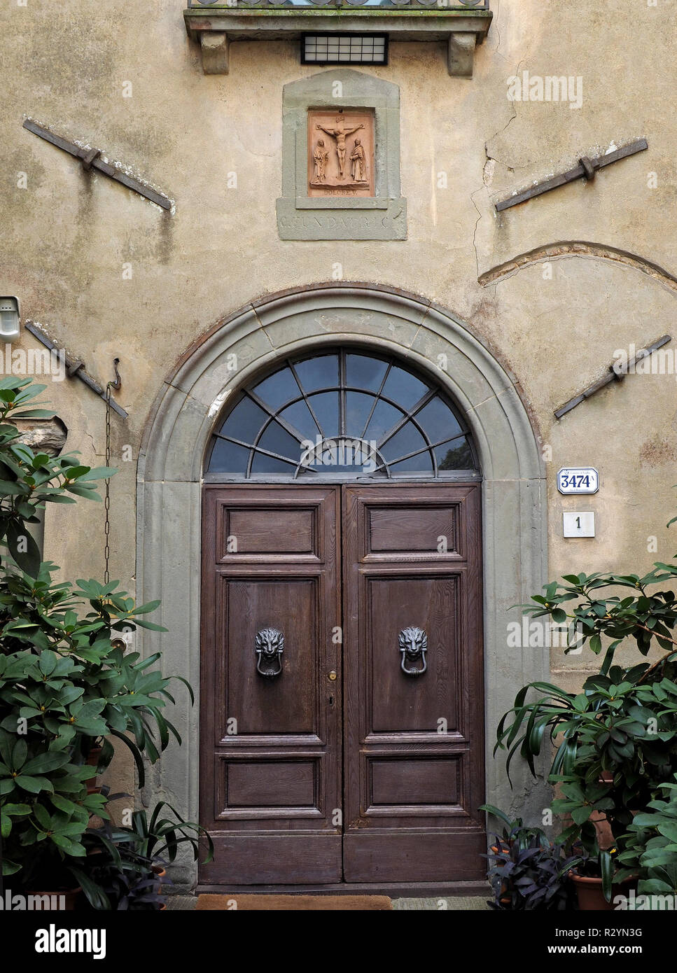 Double porte avec lion heurtoirs de porte et fenêtre en arc-en-dessous des bas-relief de la crucifixion du Christ au monastère de Montesenario, Toscane, Italie Banque D'Images