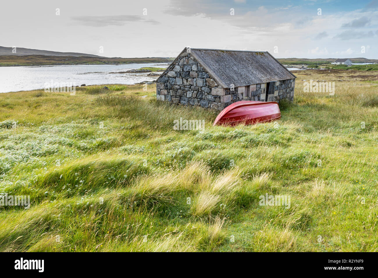 Chalet traditionnel en pierre rouge et bateau à rames par la côte, Uist, îles Hébrides, Ecosse, Royaume-Uni, Europe Banque D'Images