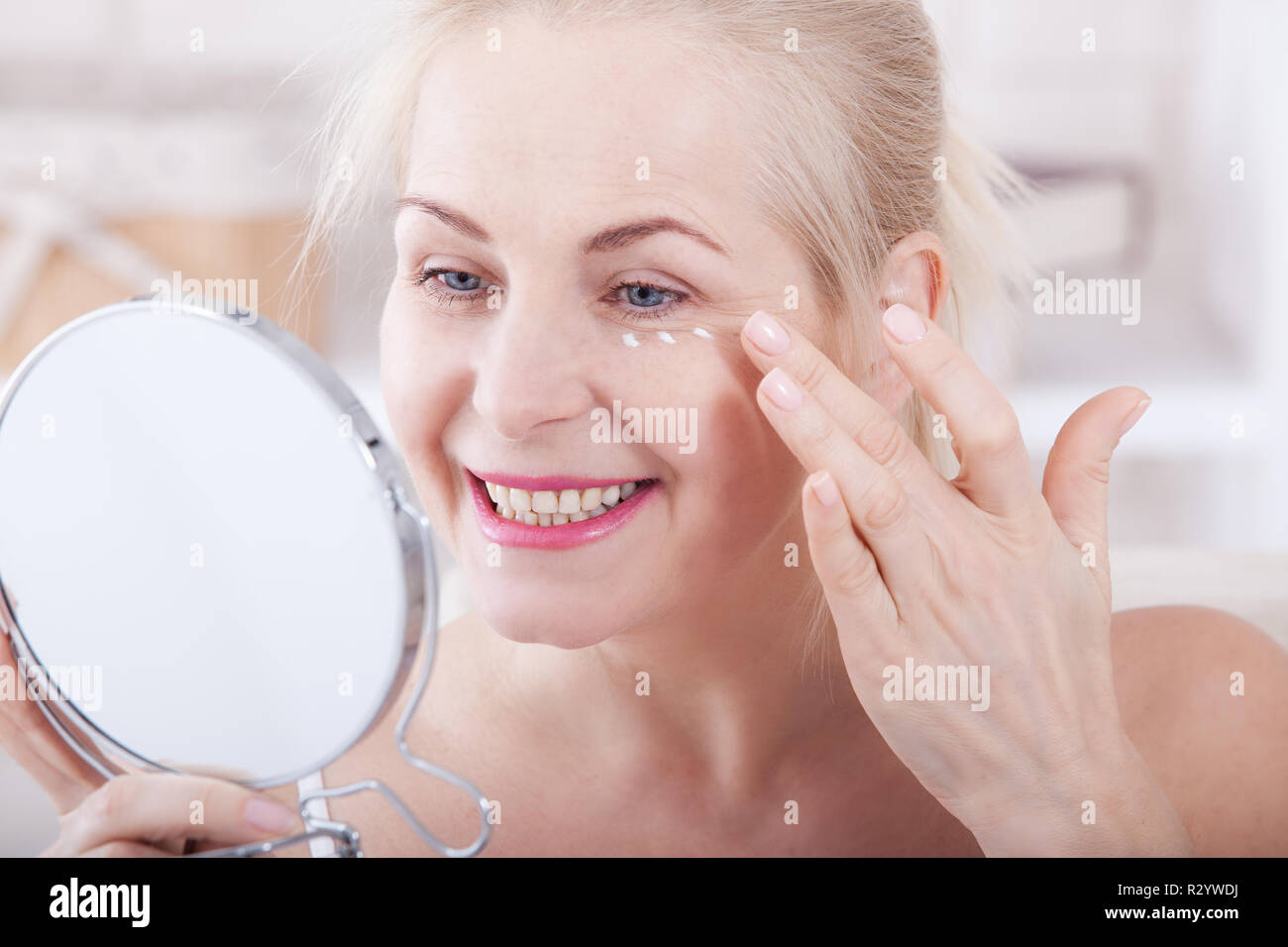 Femme d'âge moyen à la recherche de rides dans le miroir. La chirurgie plastique et les injections au collagène. Le maquillage. Visage de macro. Selective focus sur le visage. Des images réalistes avec leurs propres imperfections. Banque D'Images