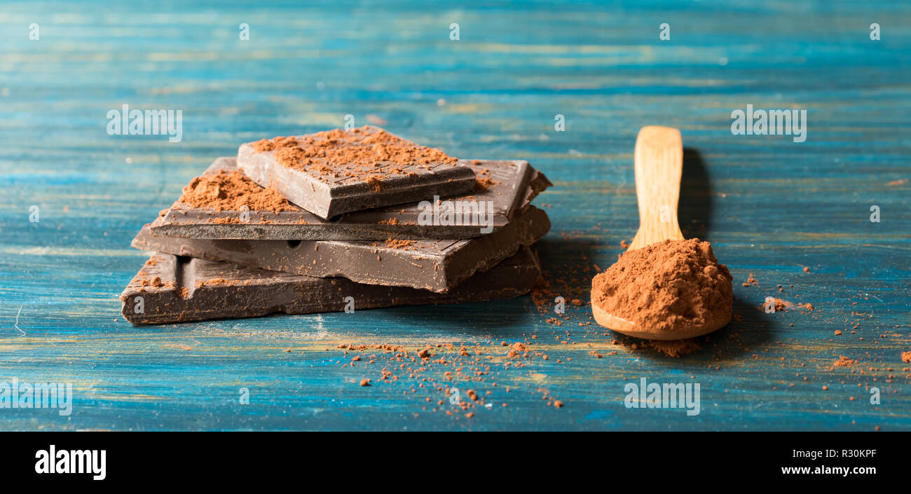 Le chocolat noir et le cacao pur dans la cuillère en bois, sur un fond de bois bleu Banque D'Images