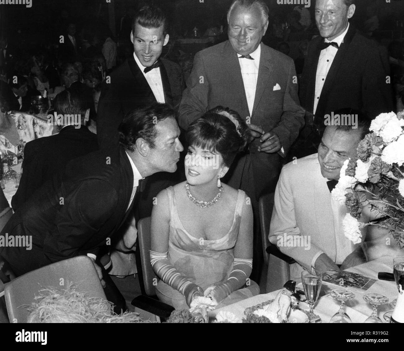 L'acteur Eddie Constantine (r) félicite son collègue italien Gina Lollobrigida pour son anniversaire le 4 juillet 1965, à l'Filmball au Palais am Funkturm avec un baiser sur la joue. Droite : directeur du Festival Alfred Bauer. Dans le monde d'utilisation | Banque D'Images