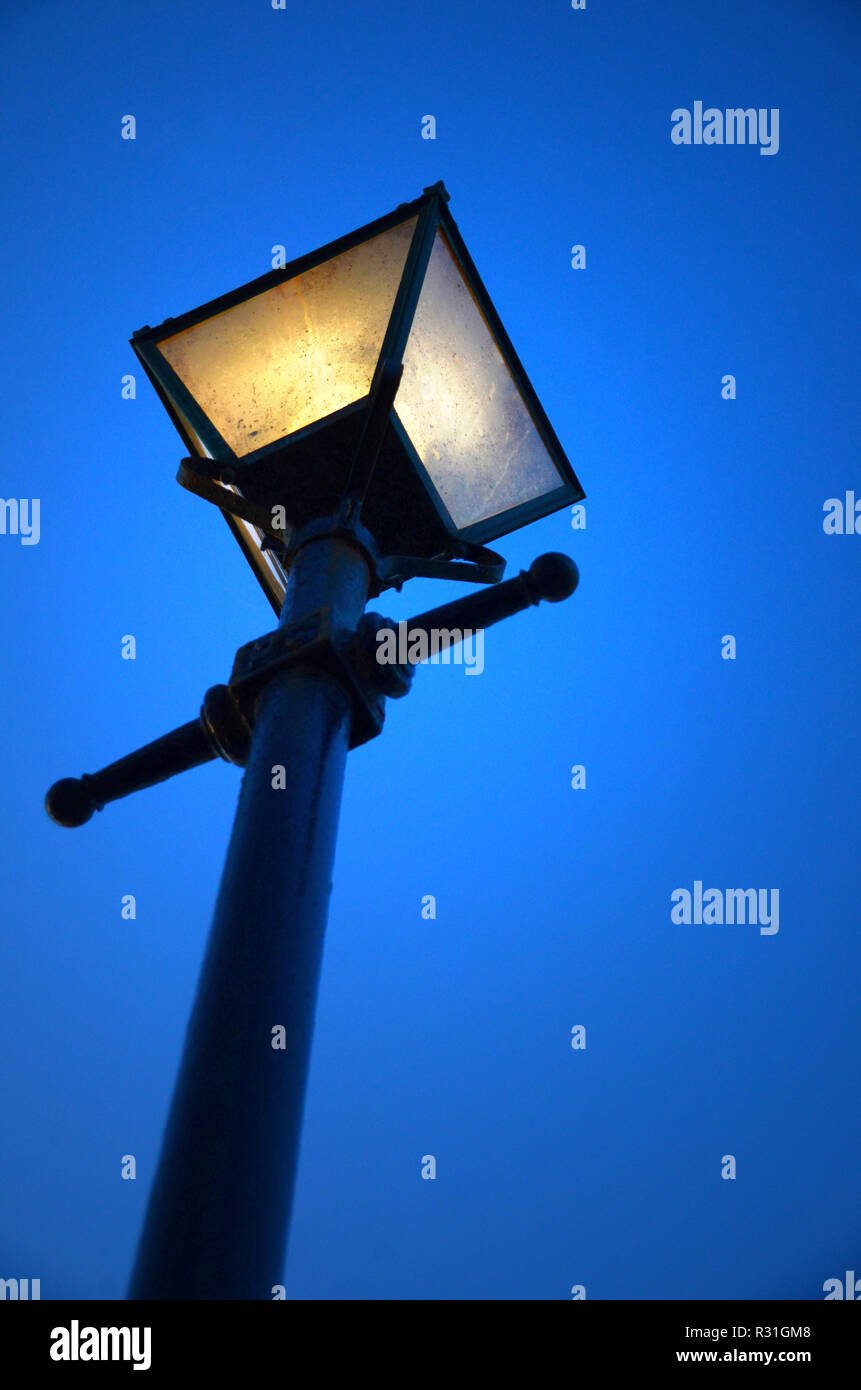 À la recherche jusqu'à un lampadaire de la rue victorien éclairé, au crépuscule.. Banque D'Images