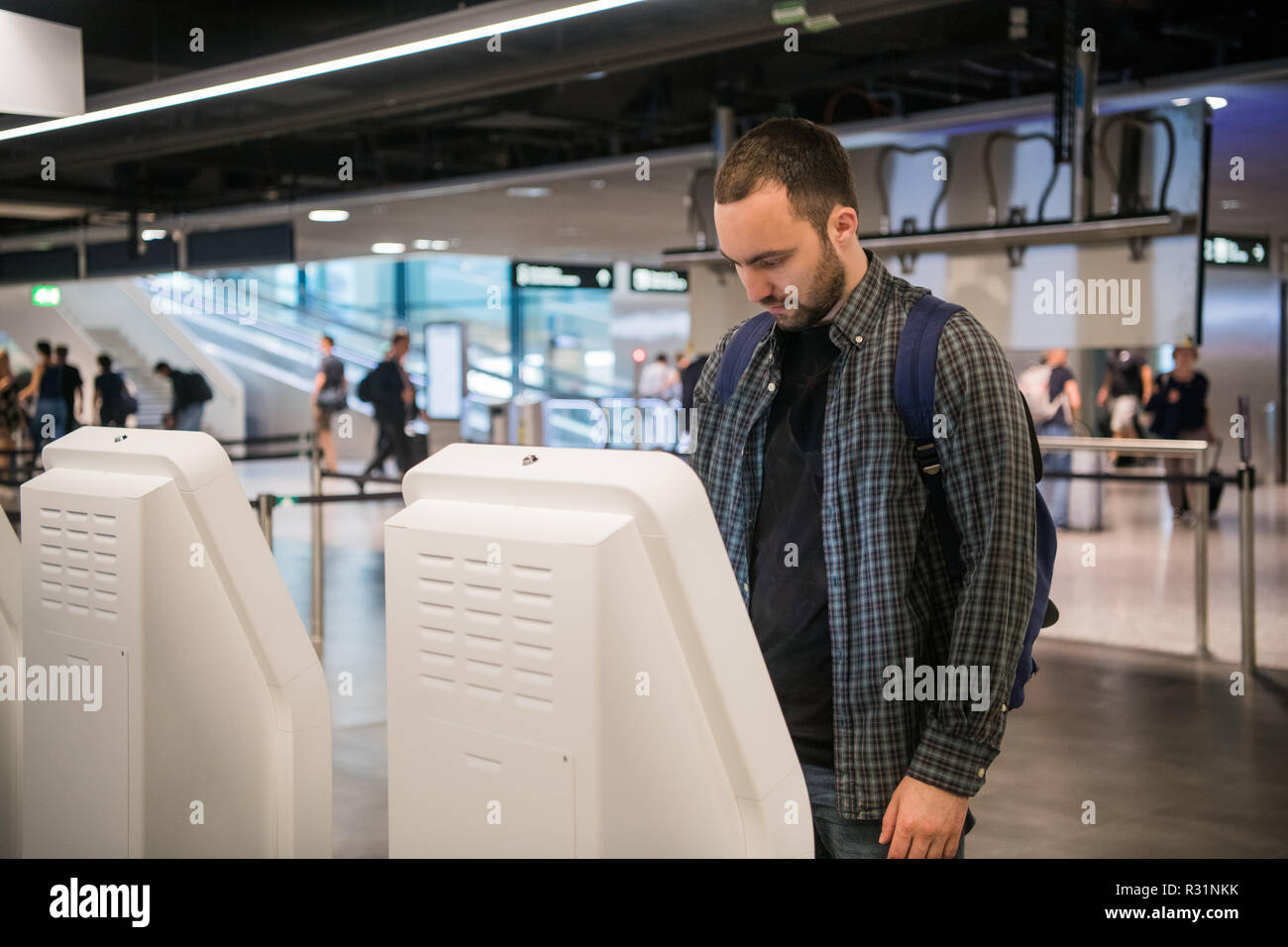 Beau jeune homme barbu faisant l'enregistrement au comptoir de la compagnie aérienne machine Banque D'Images