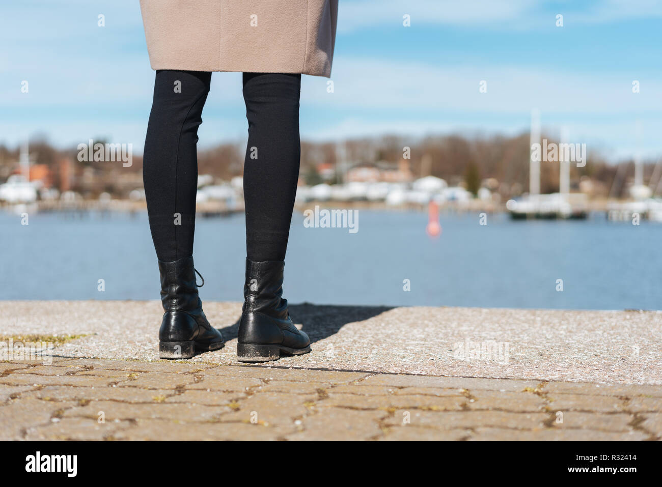 Une femme les jambes et les pieds avec des bottes, une jupe et des jambières  surplombant port dock sur une journée ensoleillée Photo Stock - Alamy