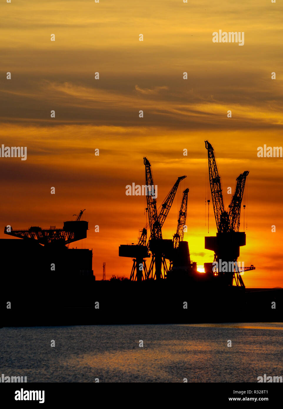 Sunset silhouette grues sur le fleuve Clyde, Glasgow, Ecosse Banque D'Images