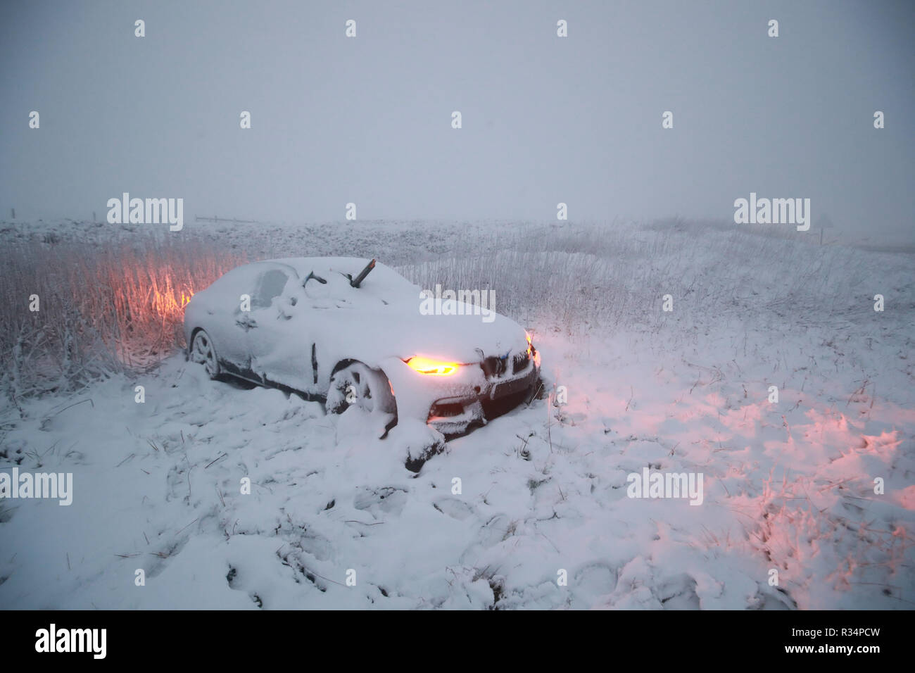 Une voiture en panne, avec un objet faisant saillie au-dessus du pare-brise, se trouve abandonné sur l'A628 dans le Peak District, comme un souffle de neige frappe le nord de l'Angleterre. Banque D'Images