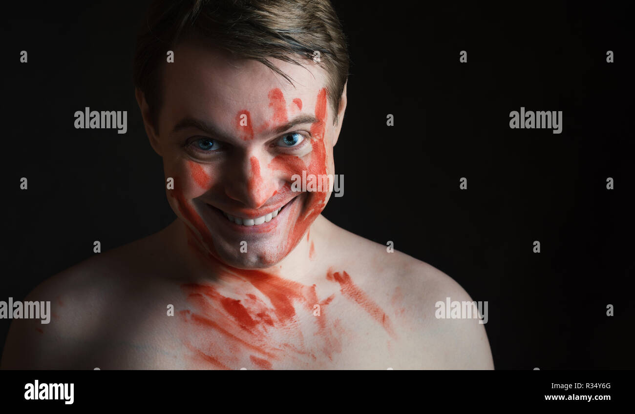 Portrait de jeune homme avec du sang sur son visage sur fond sombre. Banque D'Images