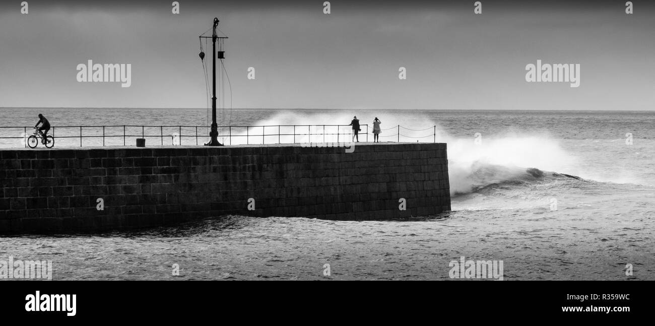 Noir et blanc de mer difficile de frapper le mur du port à Porthleven, Cornwall et tremper les spectateurs dans de grosses vagues. Banque D'Images