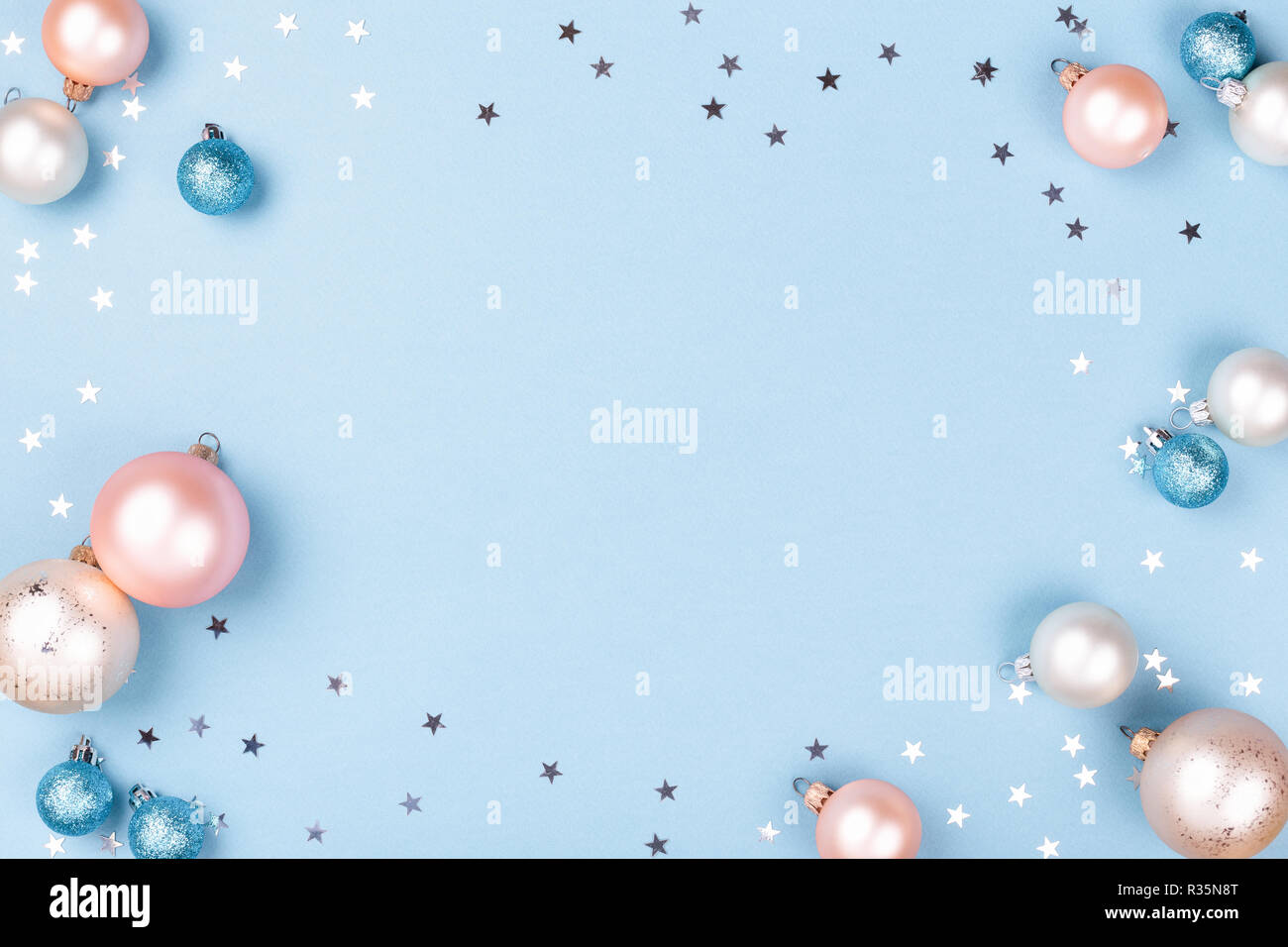 Cadre de noël faites de boules de Noël et de l'argent les confettis sur fond bleu. Un minimum de carte de Nouvel An, vue du dessus. Banque D'Images