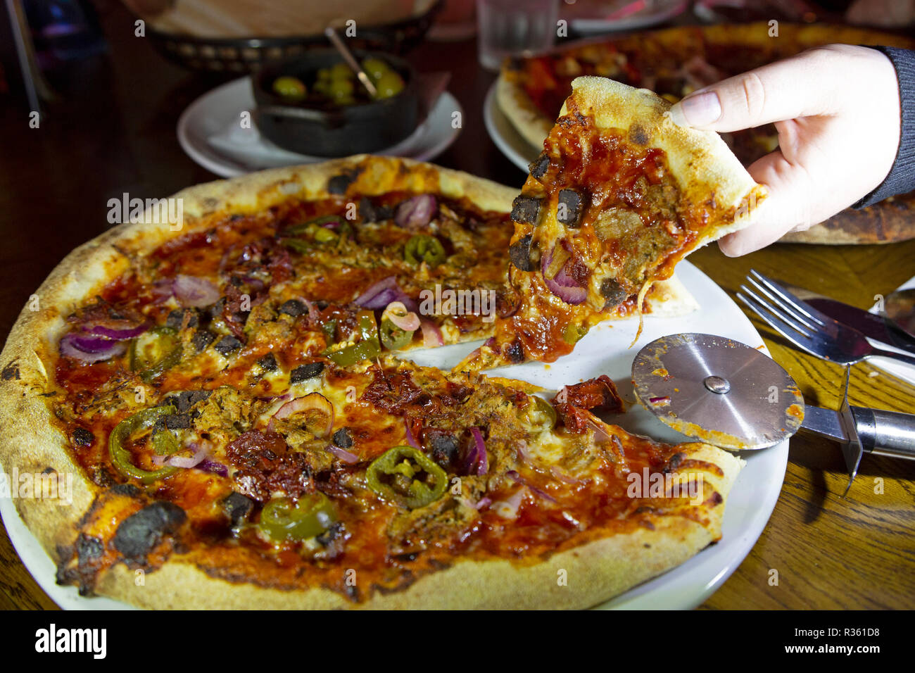 Un homme déchire une tranche de pizza d'une assiette dans un restaurant. Banque D'Images