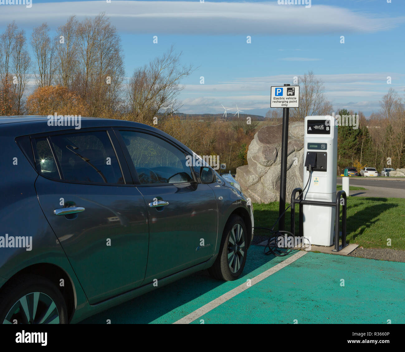 Location de véhicule électrique au point de rechargement avec les éoliennes dans l'arrière-plan Banque D'Images