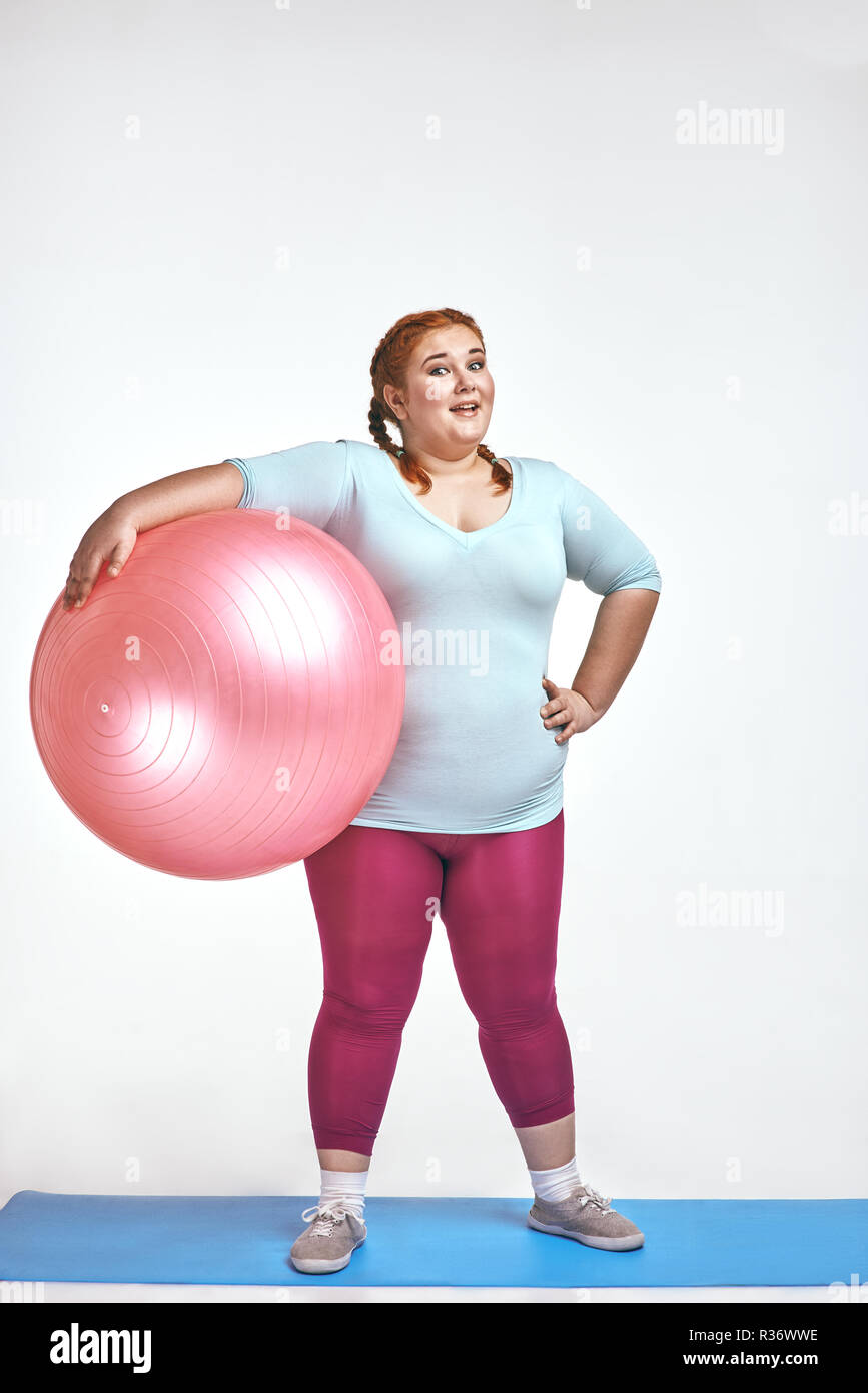 Image drôle amusant, red haired chubby, qui est femme tenant une balle Banque D'Images