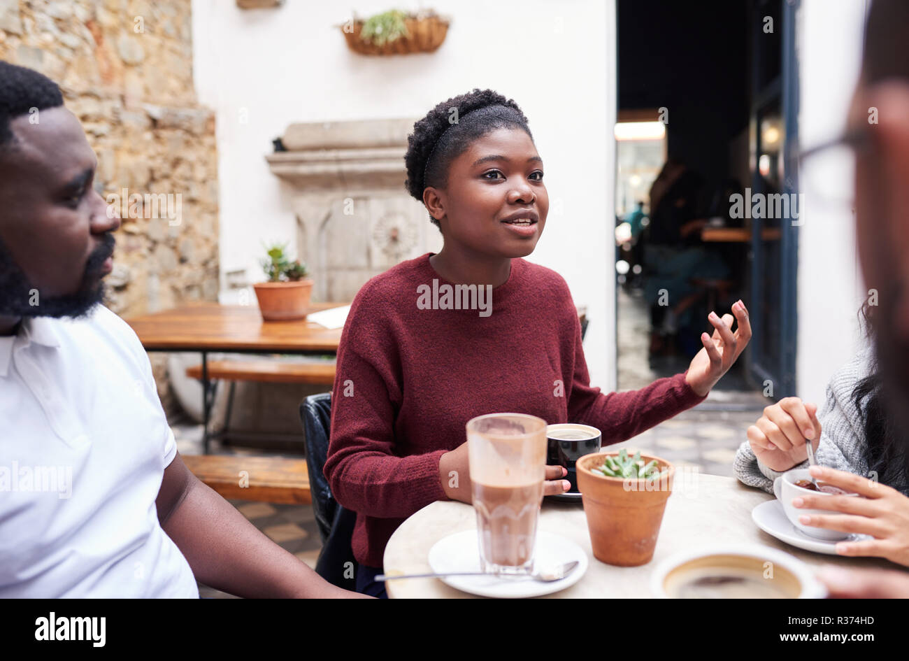 Jeune femme parlant avec des amis dans un café branché de cour intérieure Banque D'Images