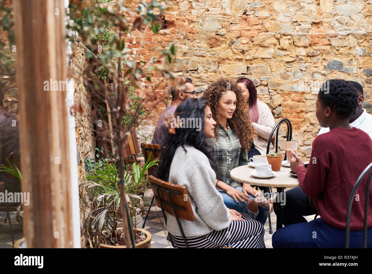 Female friends chatting over coffee dans un cafés à la cour intérieure Banque D'Images