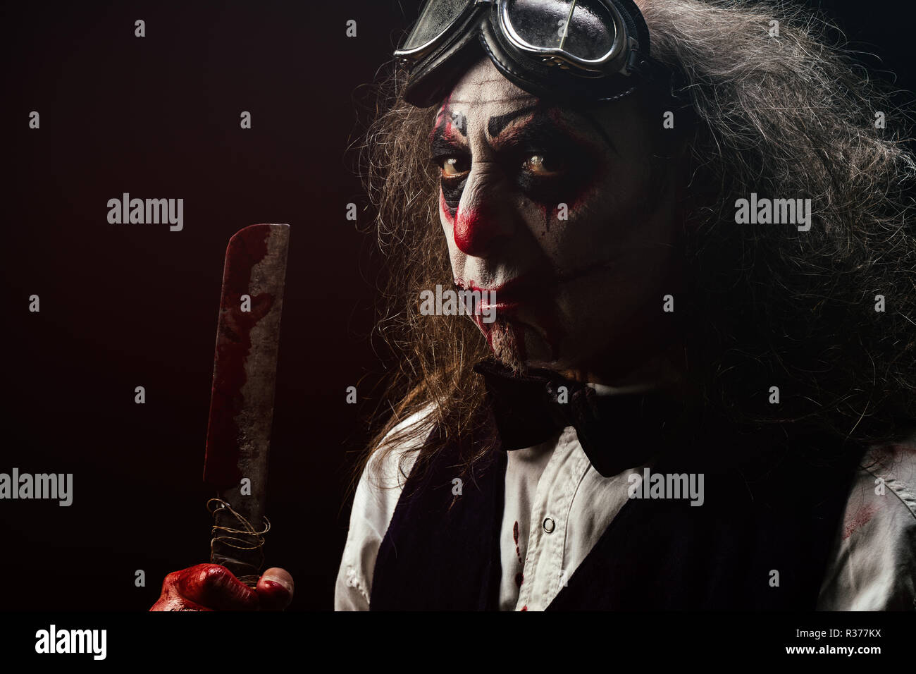 Portrait d'un clown sadique, un couteau à la main sanglante Banque D'Images