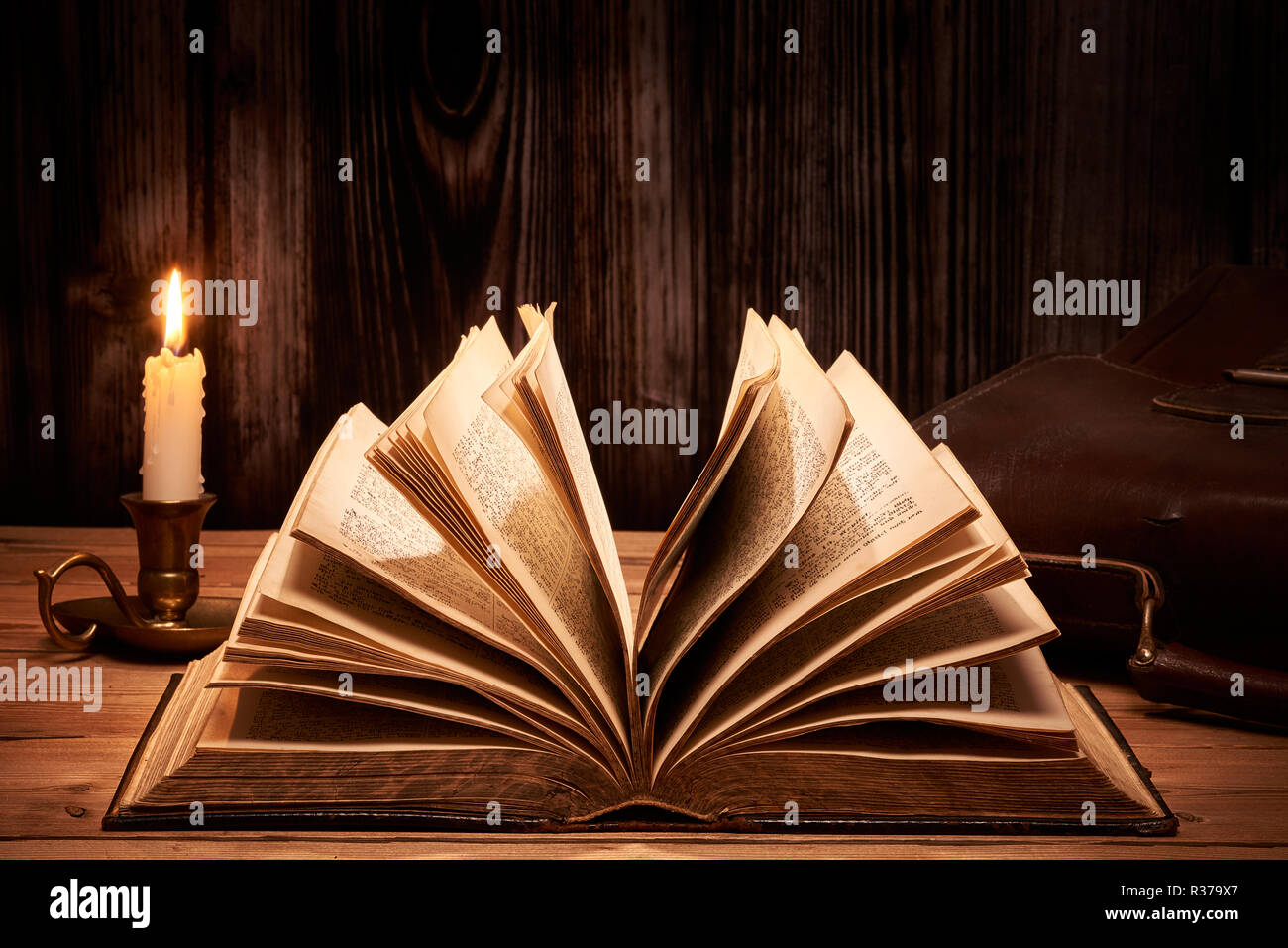 Vieux livre sur table en bois aux chandelles Banque D'Images