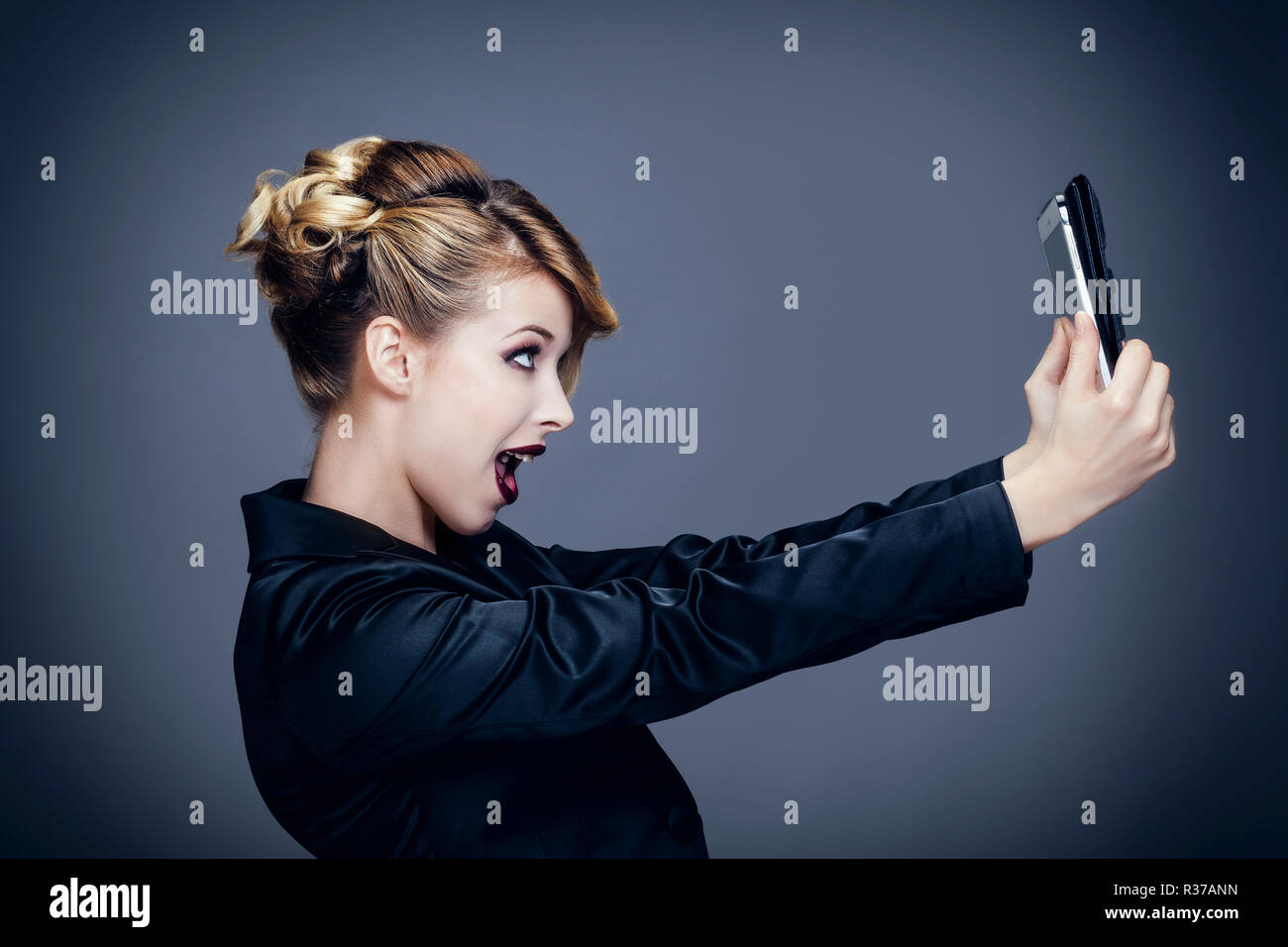 Portrait d'une jeune femme, profil, de prendre une photo avec son touch pad Banque D'Images