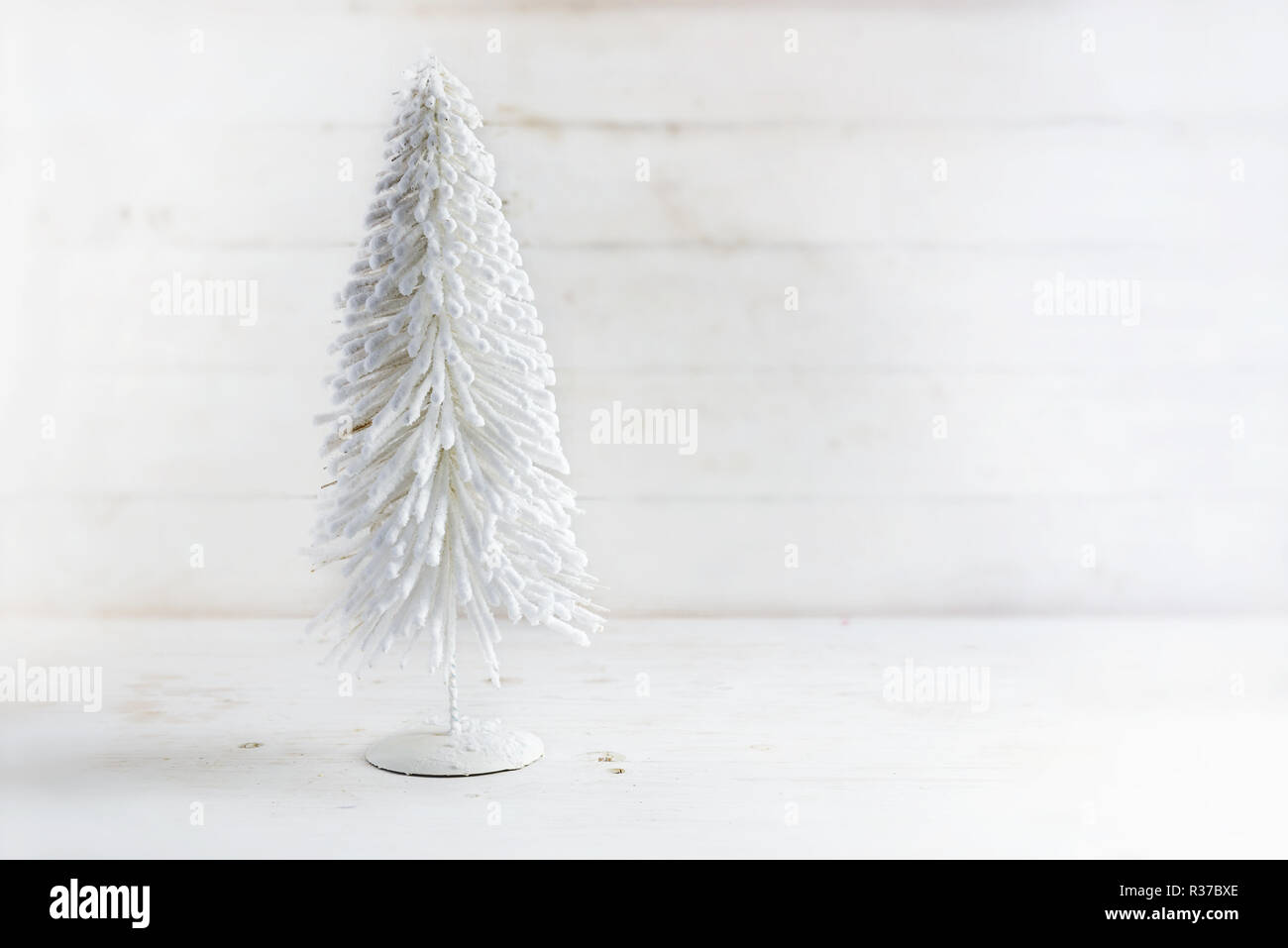 L'arbre de Noël artificiel blanc floqué de fil sur un fond de bois blanc rustique avec copie espace de discussion, Banque D'Images