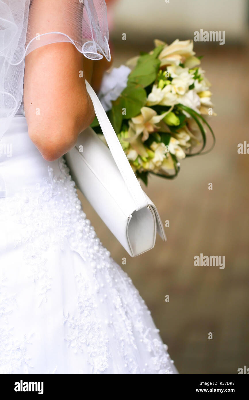 Belle robe de mariage sur une mariée avec voile, sac à main blanc et beau  bouquet dans les mains Photo Stock - Alamy
