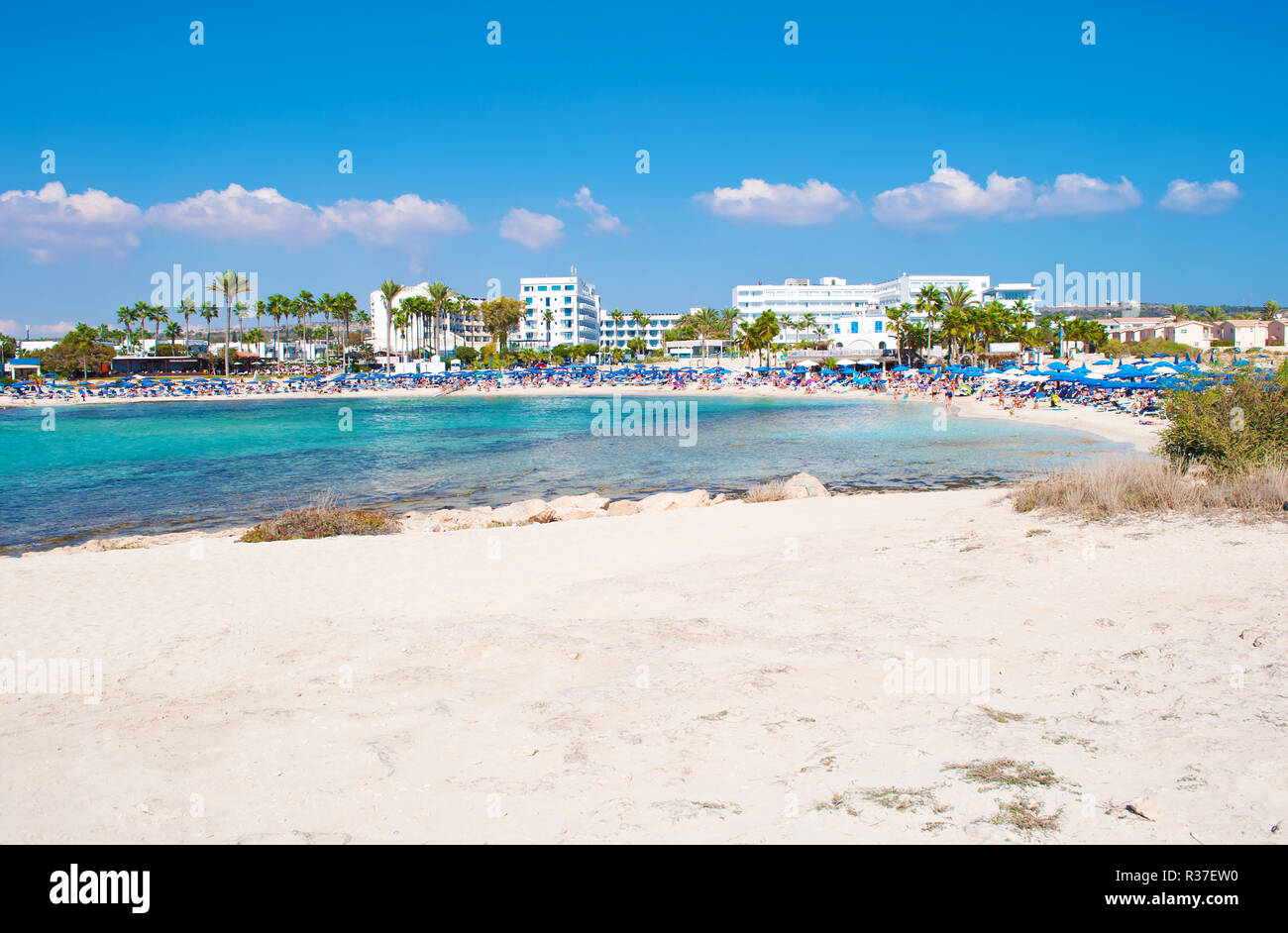Image de Vathia Gonia beach près de Agia Napa, Chypre. Sable blanc et mer bleu turquoise avec de l'eau dans une baie et maisons en arrière-plan. Chaude journée de fa Banque D'Images