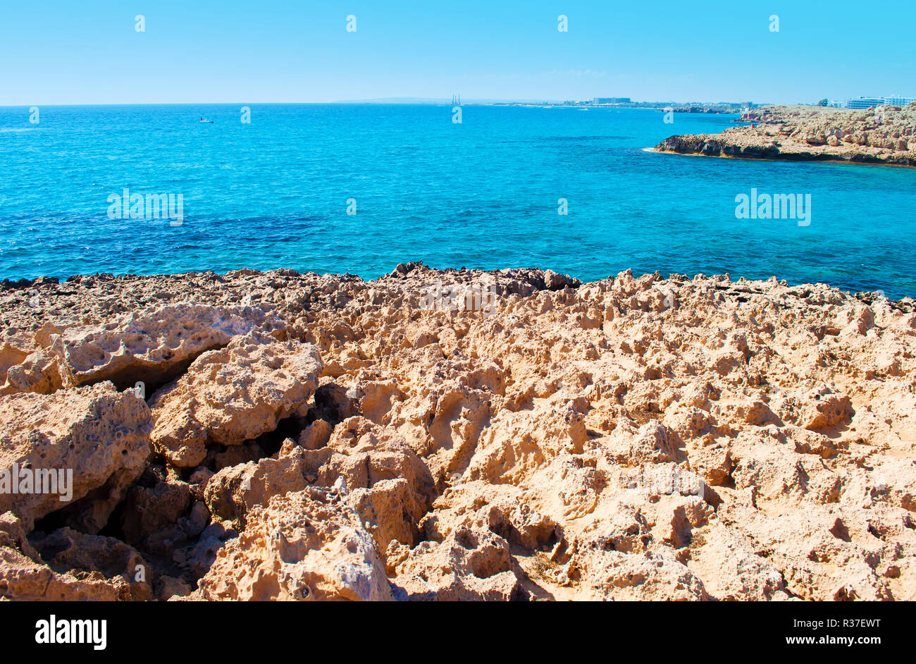 Image d'une baie près de plage Vathia Gonia, Agia Napa, Chypre. Littoral calcaire rugueux près de l'eau d'un bleu profond et rocky hill sur l'arrière-plan. Journée chaude je Banque D'Images