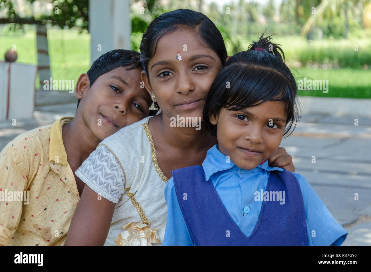 Trois jeunes frères et sœurs indiennes, un garçon, deux filles, pose devant l'appareil photo quelque part dans la région de Ranganatha, Anegundi, Karnataka, Inde Banque D'Images