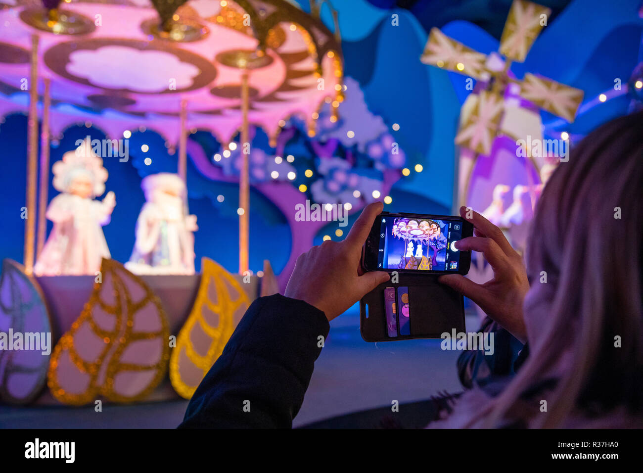 Disney Land Paris, France, Novembre 2018 : femme de prendre une photo avec son smartphone à l'intérieur petit monde une promenade en bateau à l'attraction. Banque D'Images