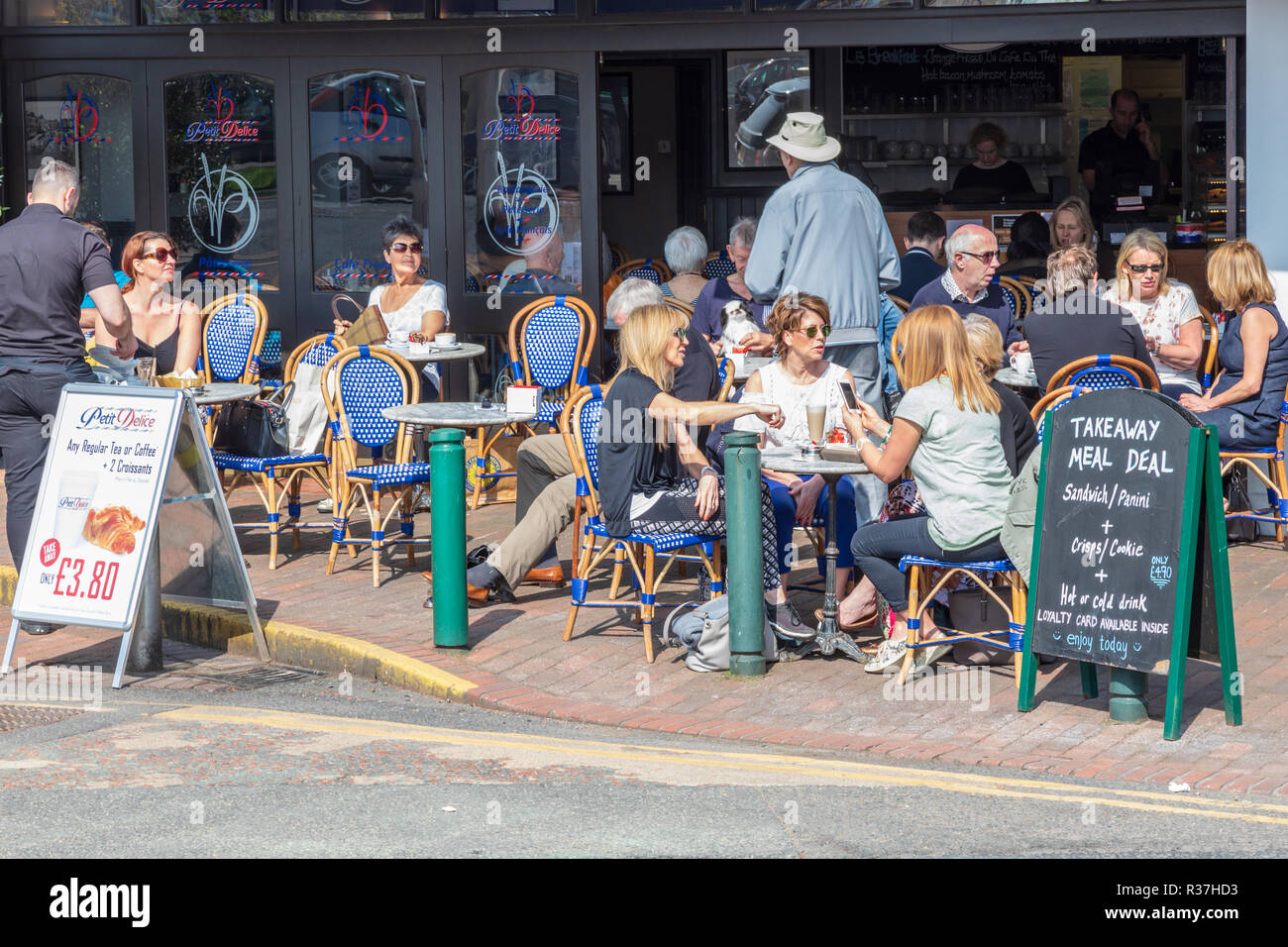 Les clients de manger et boire à la terrasse d'un café sur une journée de printemps ensoleillée. Le café est par la route à Wilmslow, Cheshire, Angleterre Banque D'Images