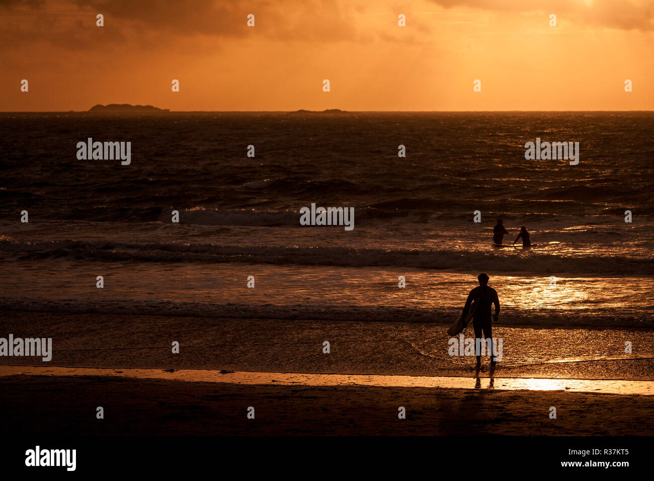 Les surfeurs en silhouette à Whitesands Bay sur la côte du Pembrokeshire, Pays de Galles du Sud Banque D'Images