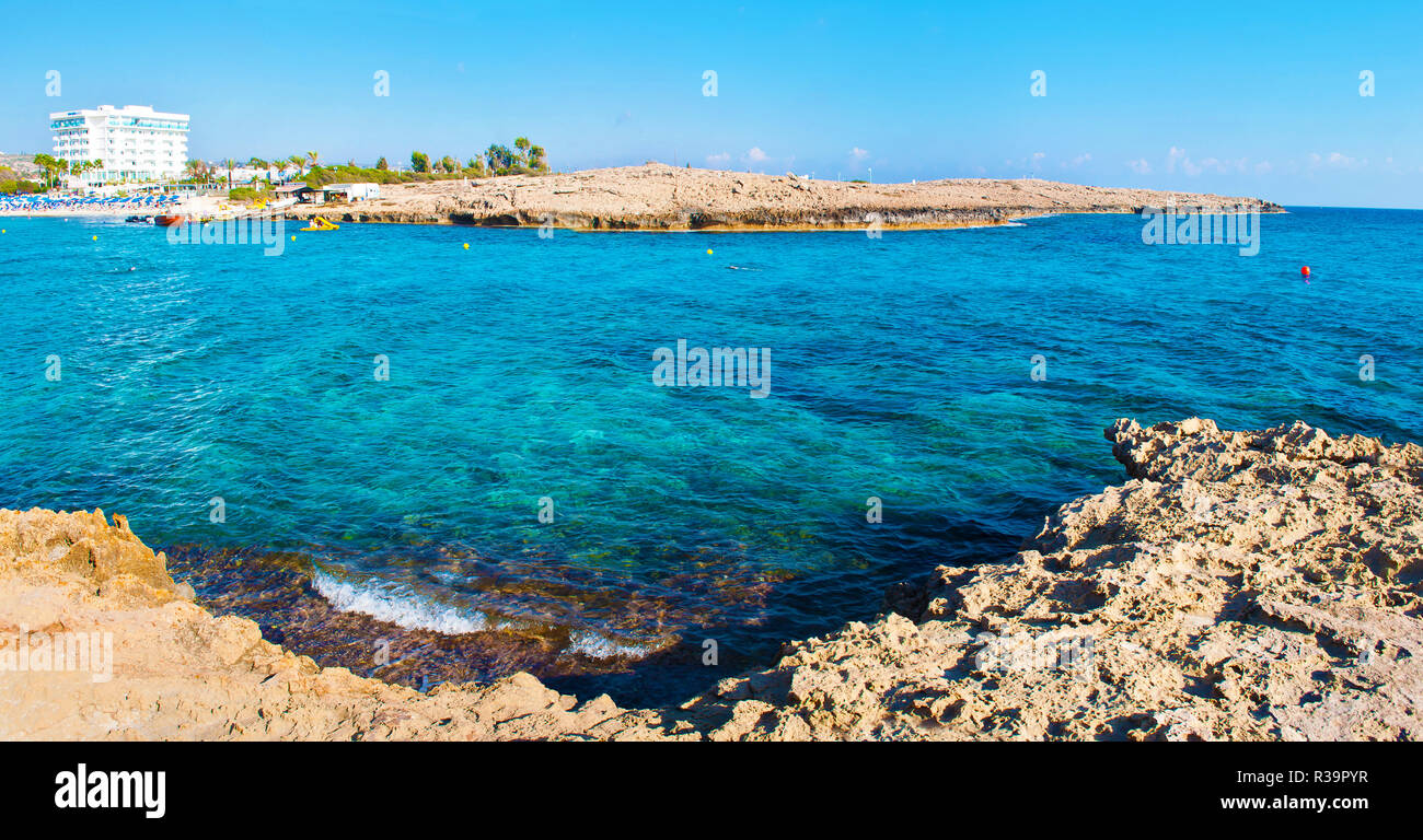 Image panoramique de la baie près de plage Vathia Gonia, Agia Napa, Chypre. Littoral calcaire rugueux près de l'eau bleu transparente contre rocky hill sur Banque D'Images