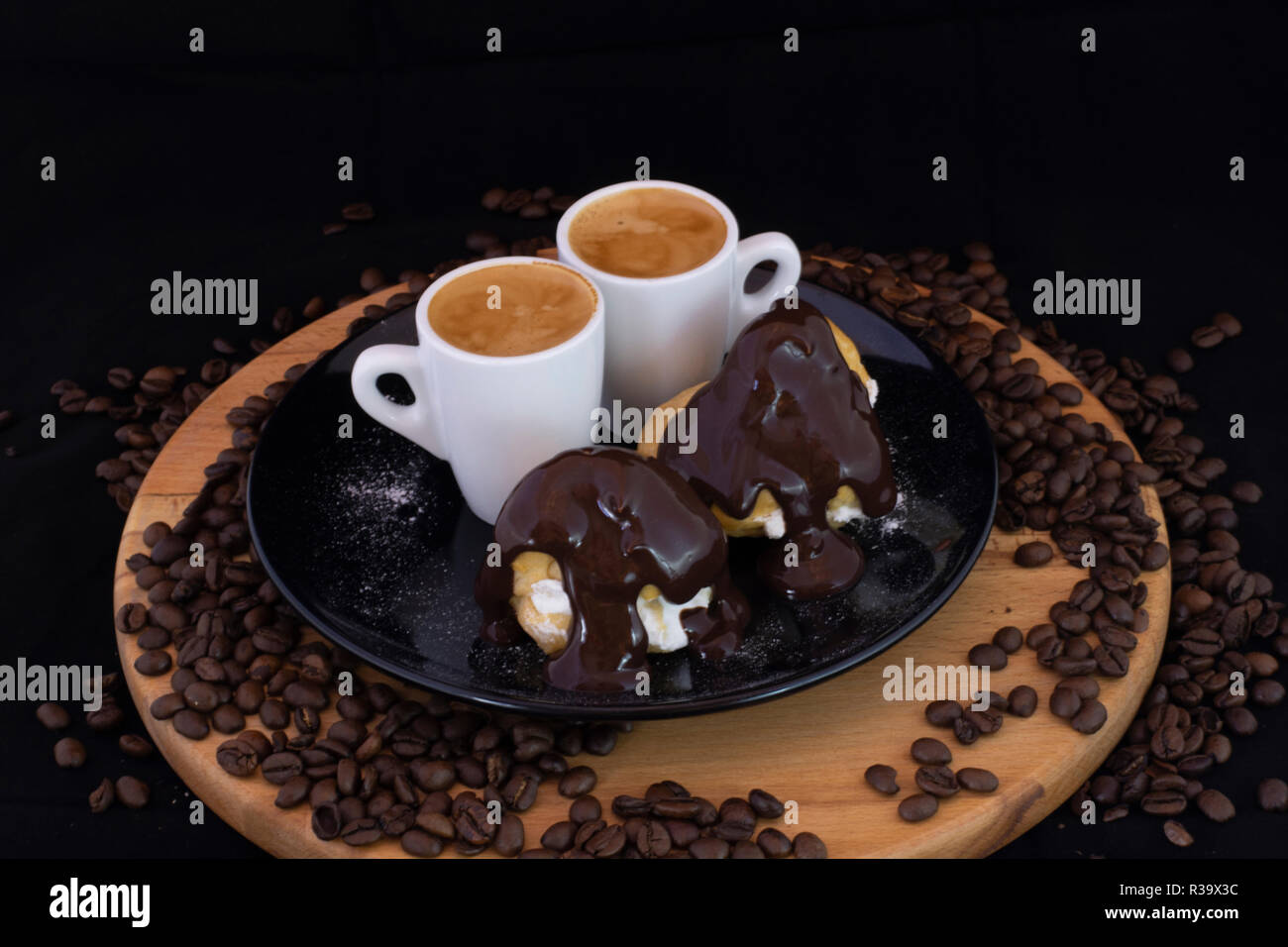 Profiterols et espresso sur bois avec fond noir isolé Banque D'Images