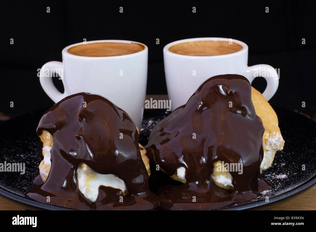 Profiterols et espresso sur bois avec fond noir isolé Banque D'Images