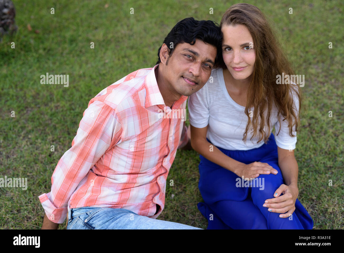Multi Ethnic couple sitting on the prairie dans l'amour à la gr Banque D'Images