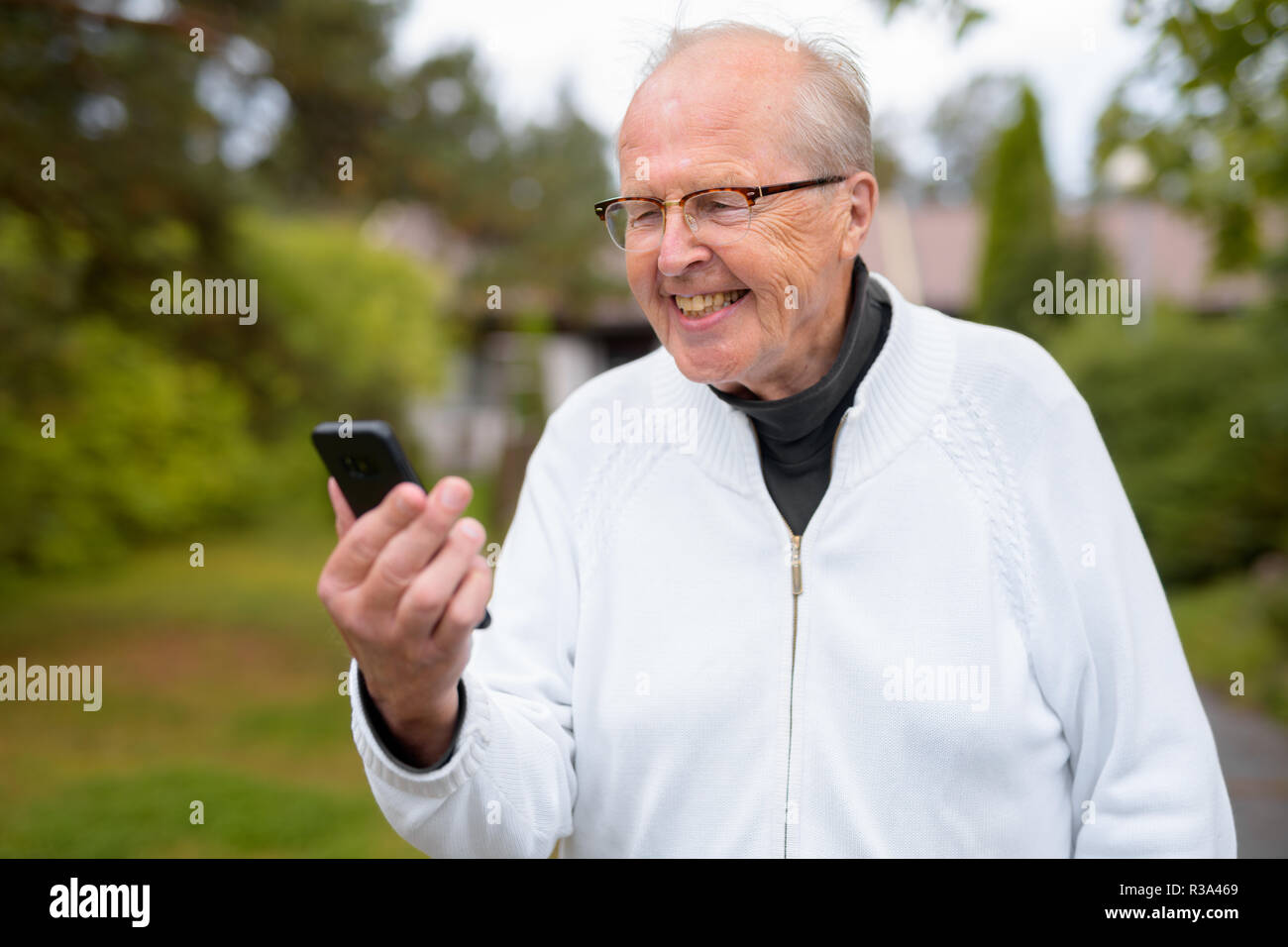 Happy Senior Man Smiling lors de l'utilisation de téléphone à la maison en plein air Banque D'Images